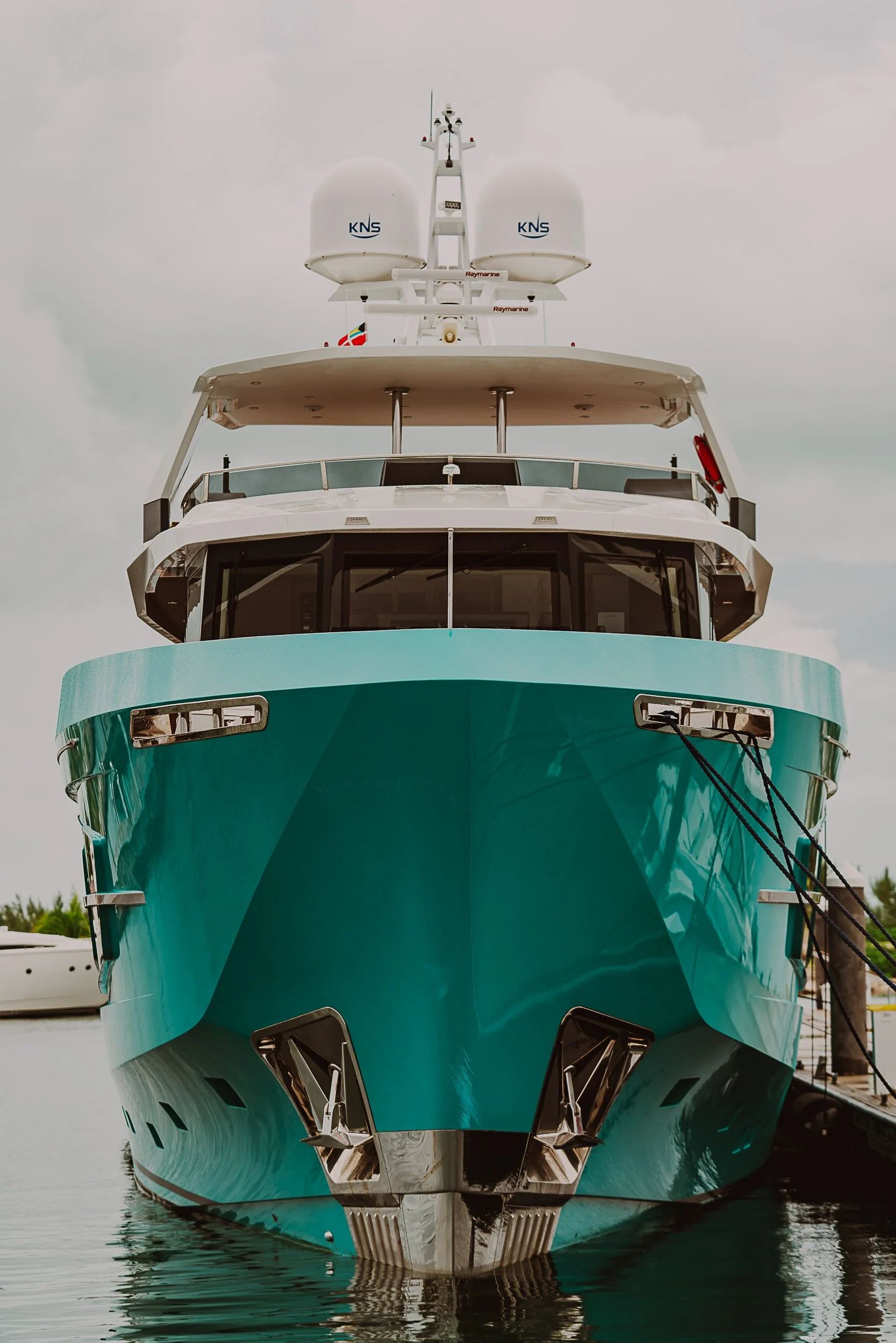 Front view of a large teal yacht docked in the water