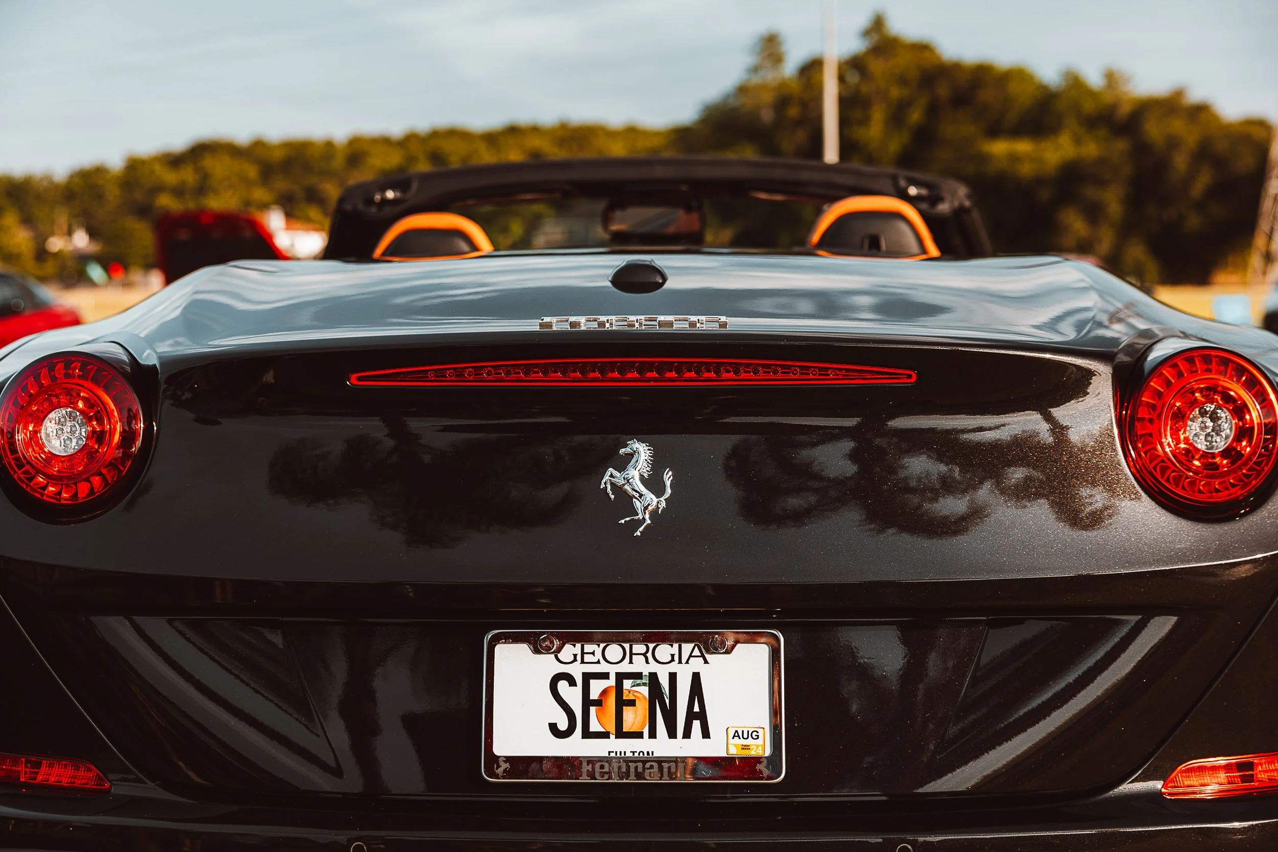 Rear view of a black Ferrari convertible with a Georgia license plate and red taillights.