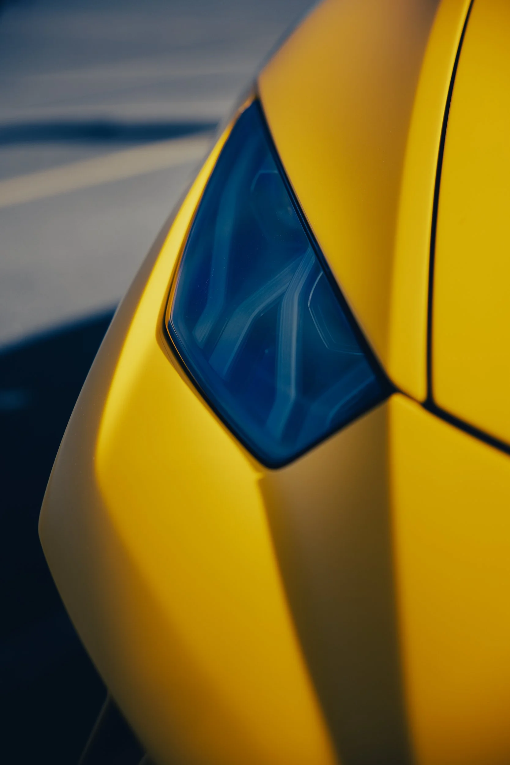 Close-up of the headlight and yellow body of a modern yellow sports car.