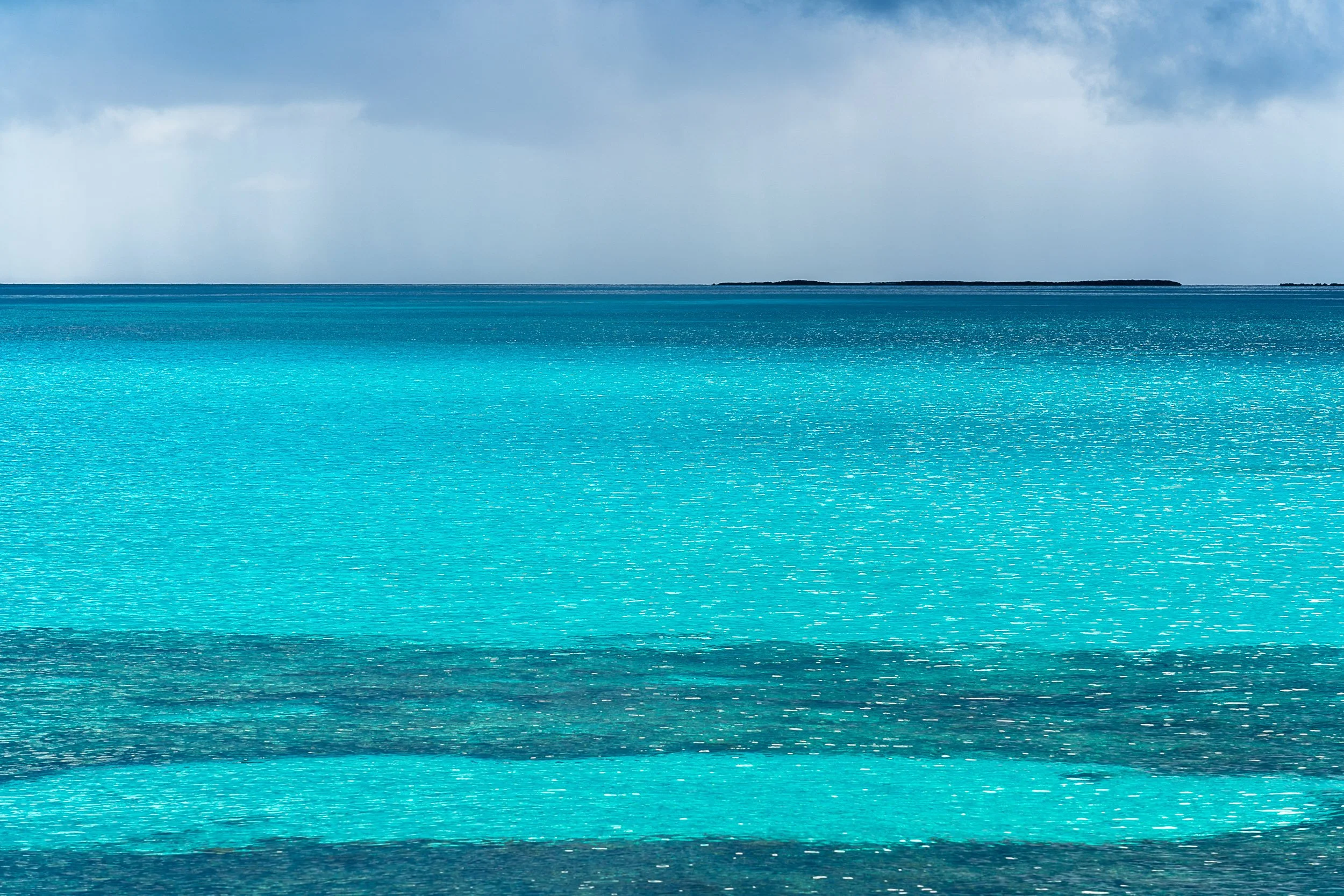 Turquoise ocean water with distant horizon and small landmass