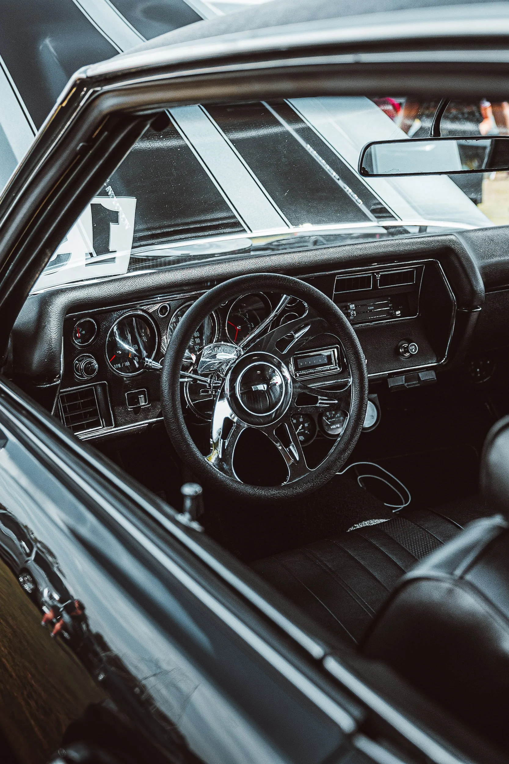 Interior of a classic car with chrome steering wheel and dashboard gauges.