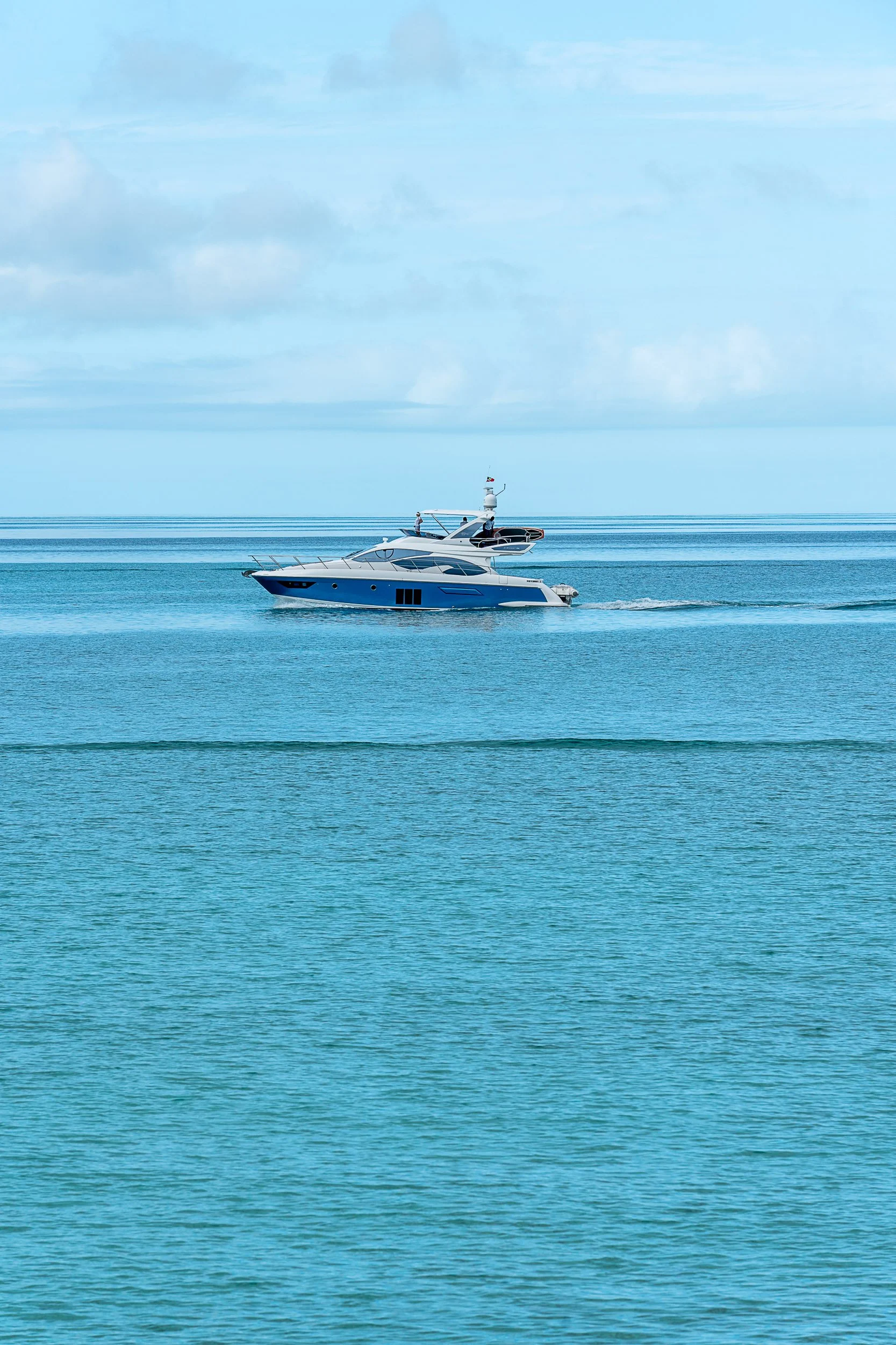 Luxury yacht cruising on calm blue ocean under a clear sky.