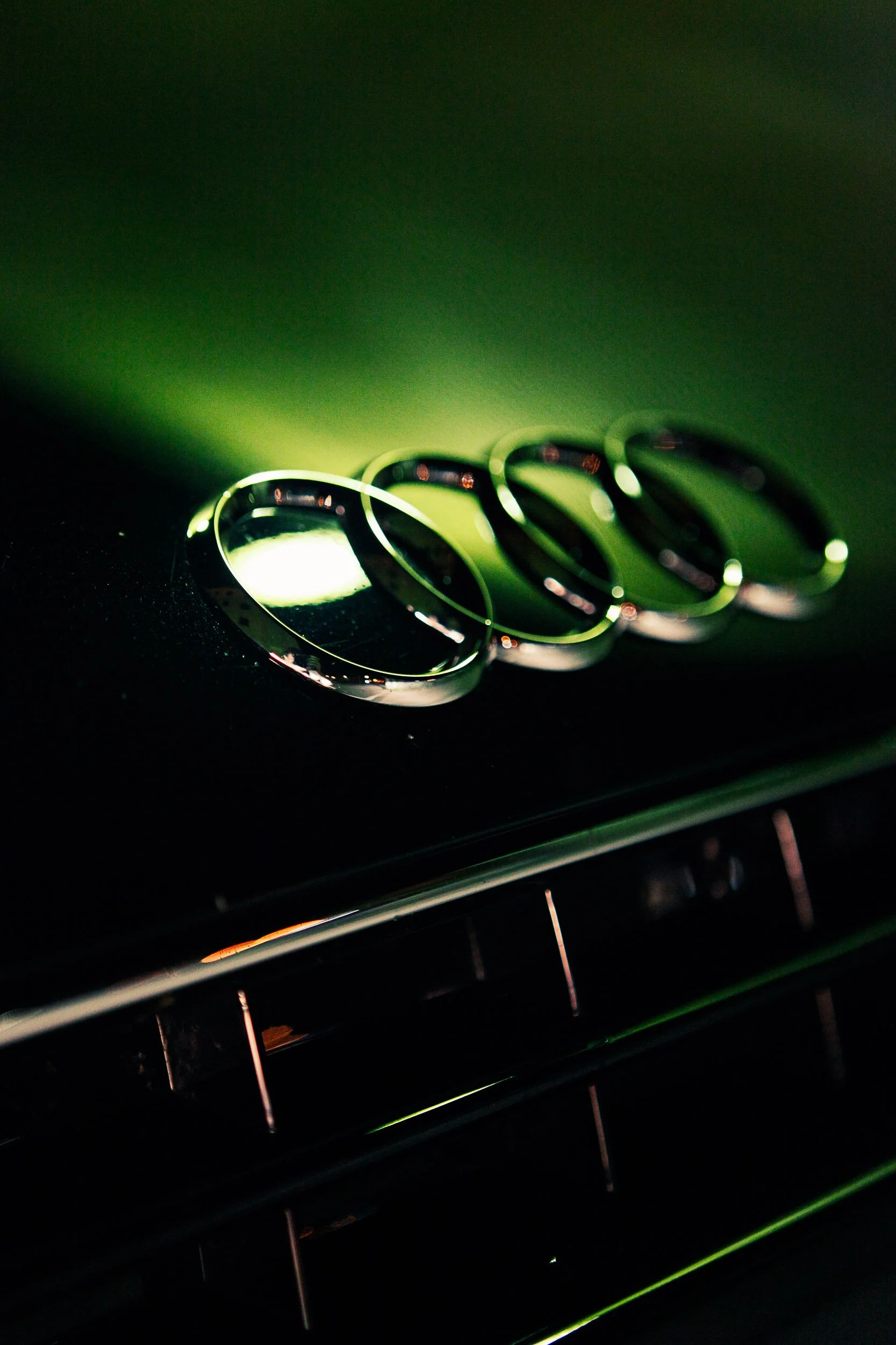 Close-up of Audi logo on car grille with green lighting