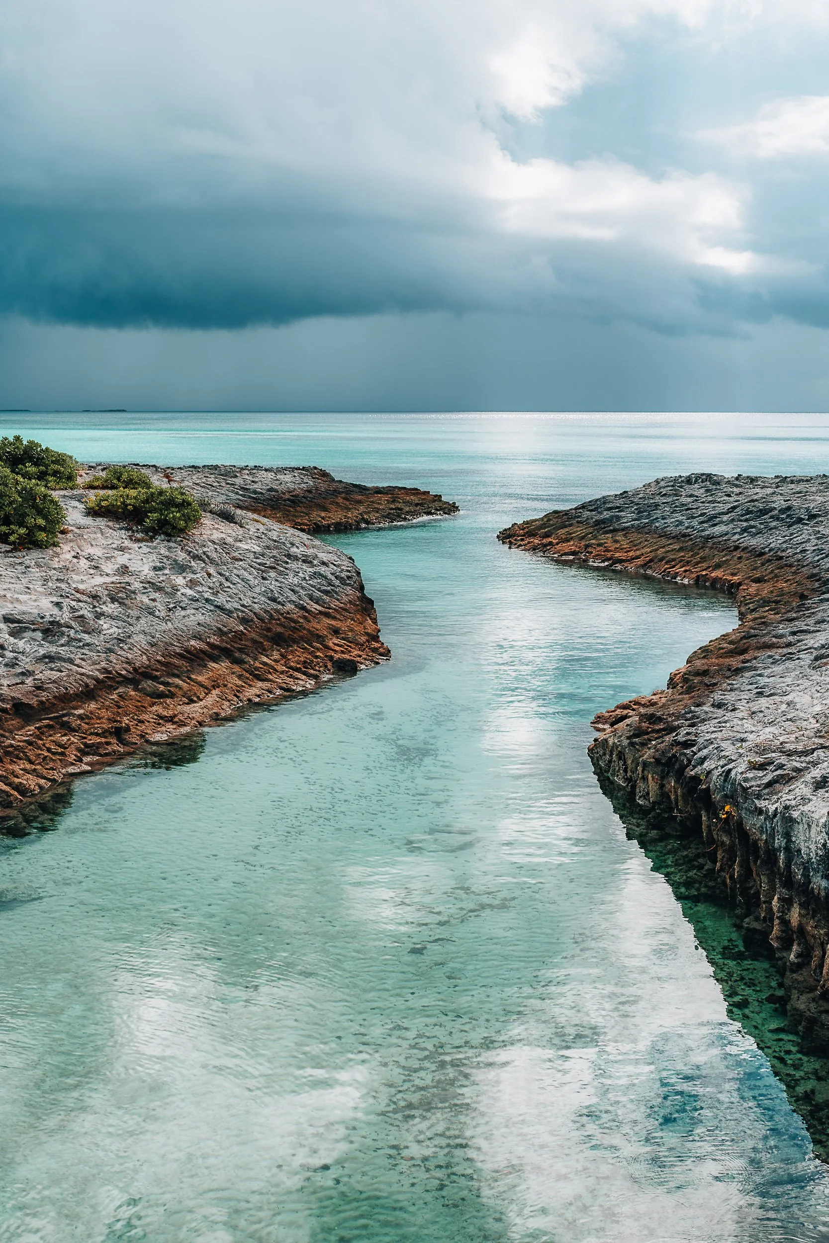Turquoise water flowing between rocky cliffs under a cloudy sky.