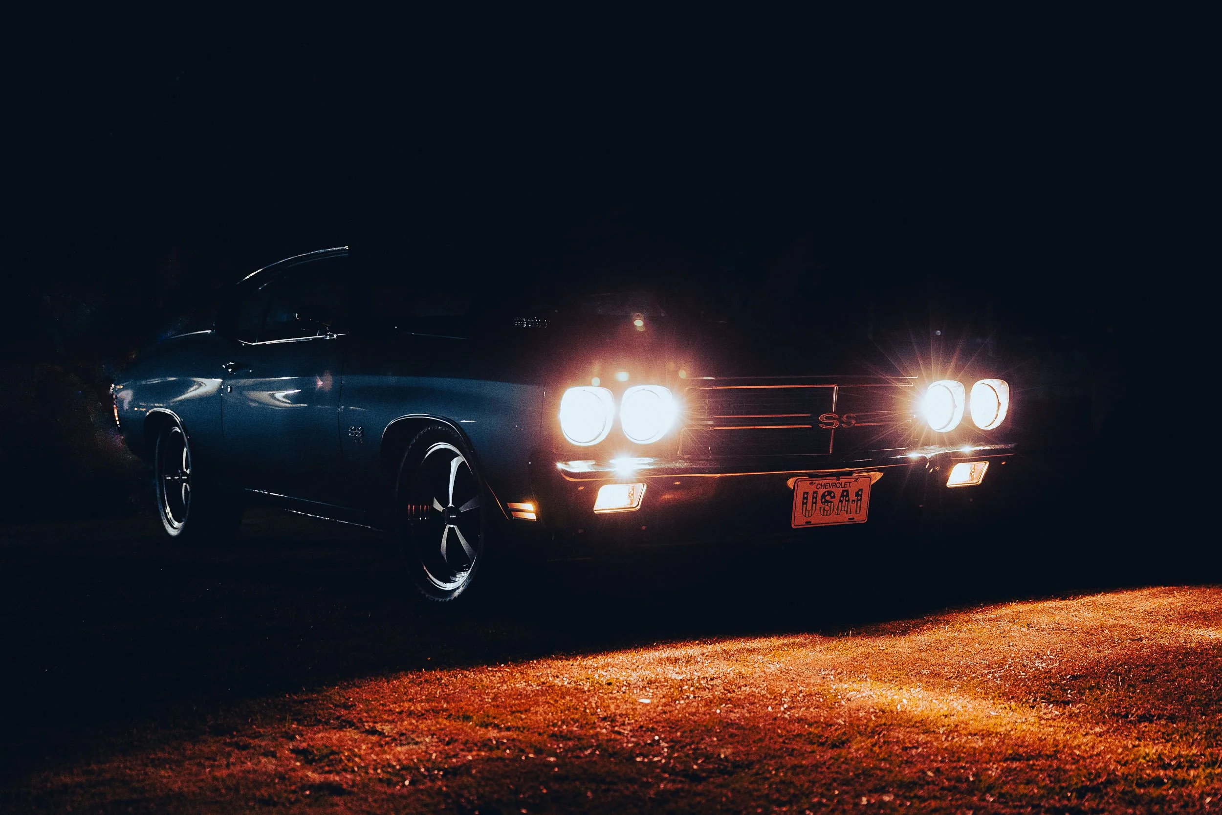 Classic car with headlights on at night