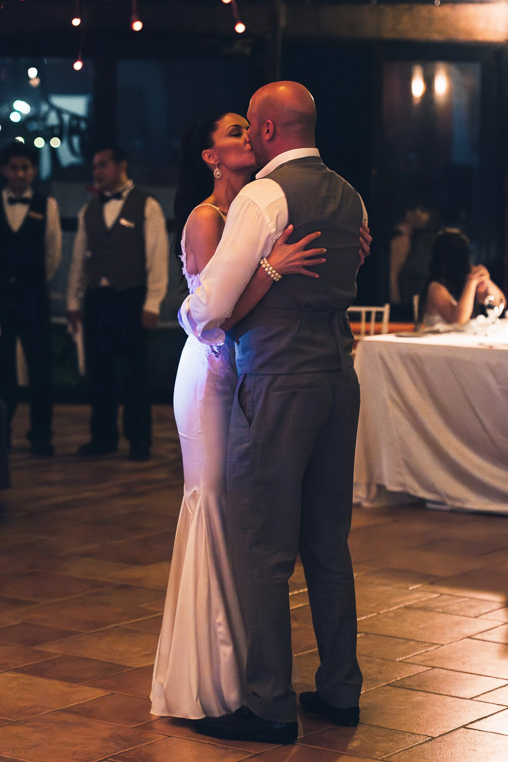 Bride and groom kissing during wedding dance.