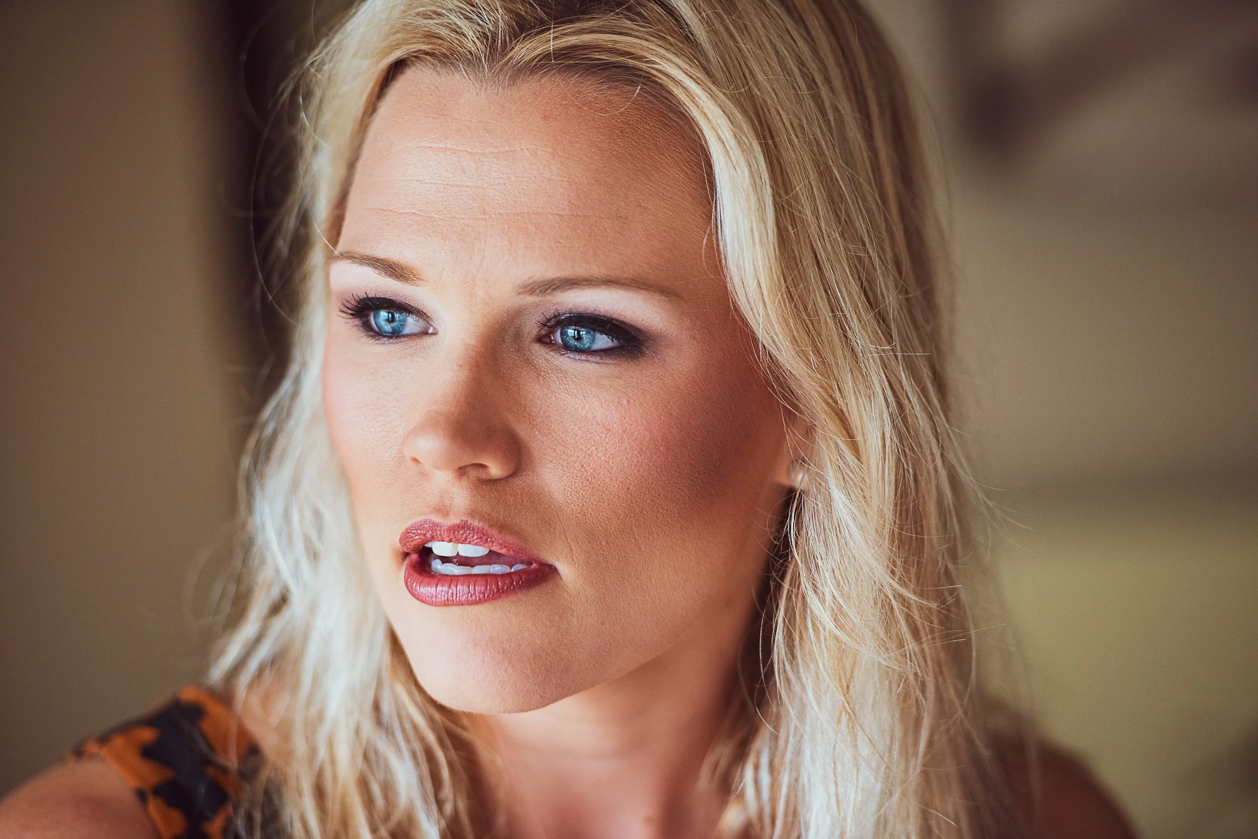 Close-up of a woman with blonde hair, blue eyes, and wearing makeup, looking to the side.