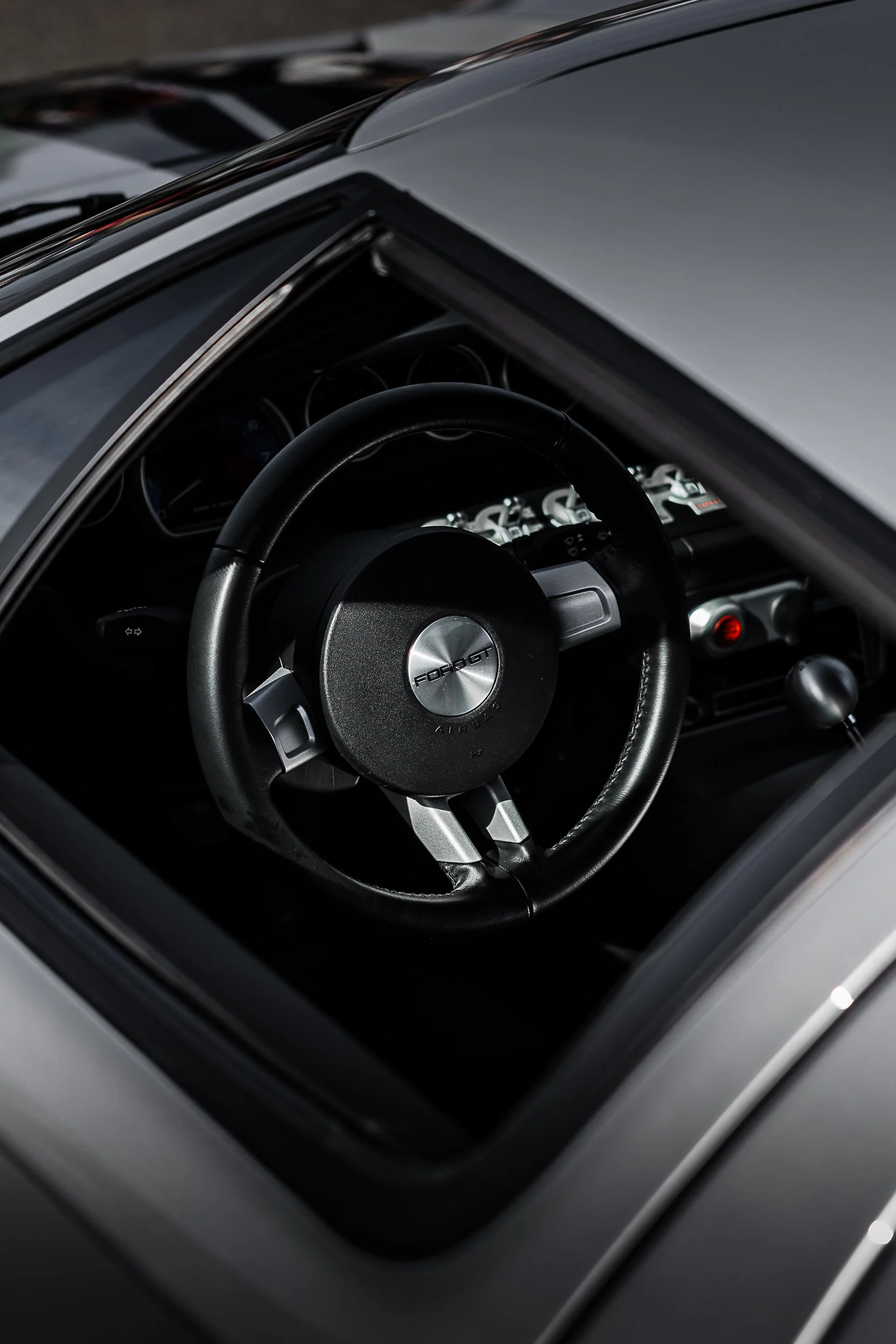 Close-up of a vintage Ford GT car's interior dashboard, steering wheel, and part of the windshield.