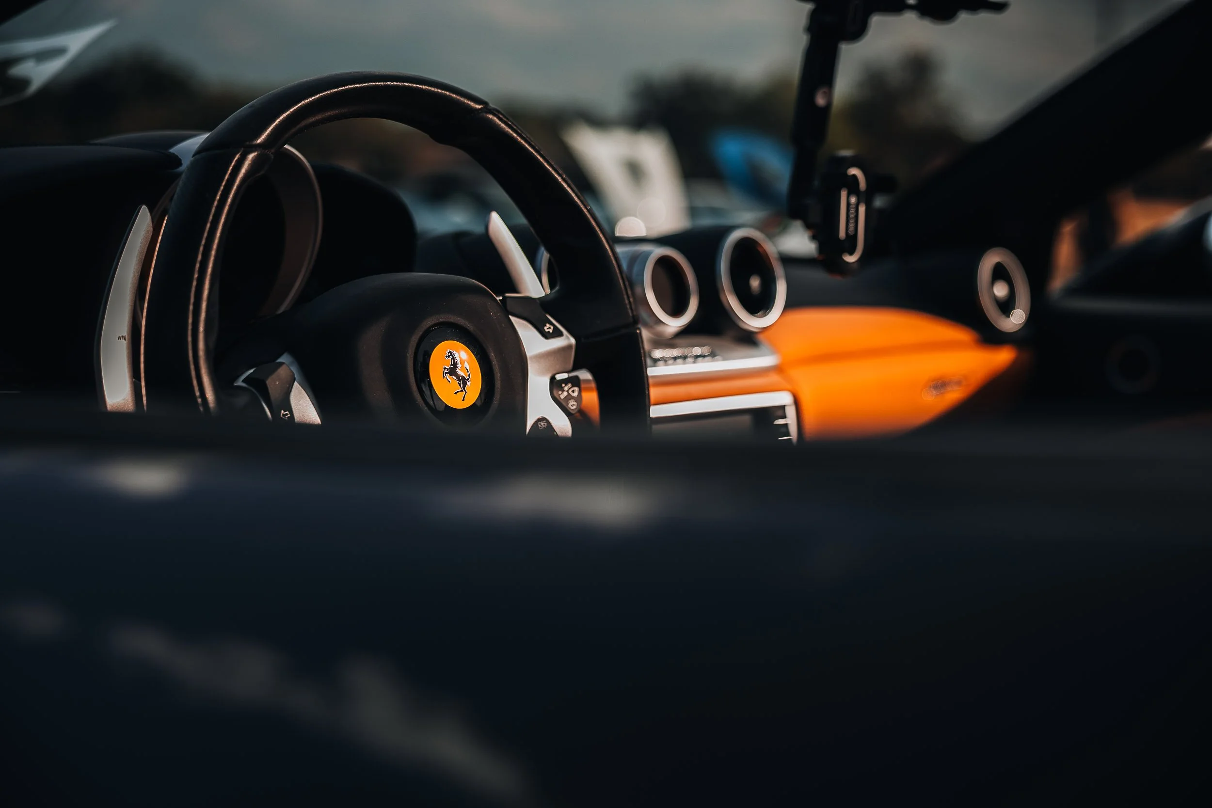 Interior view of a sports car with a branded steering wheel and orange dashboard.