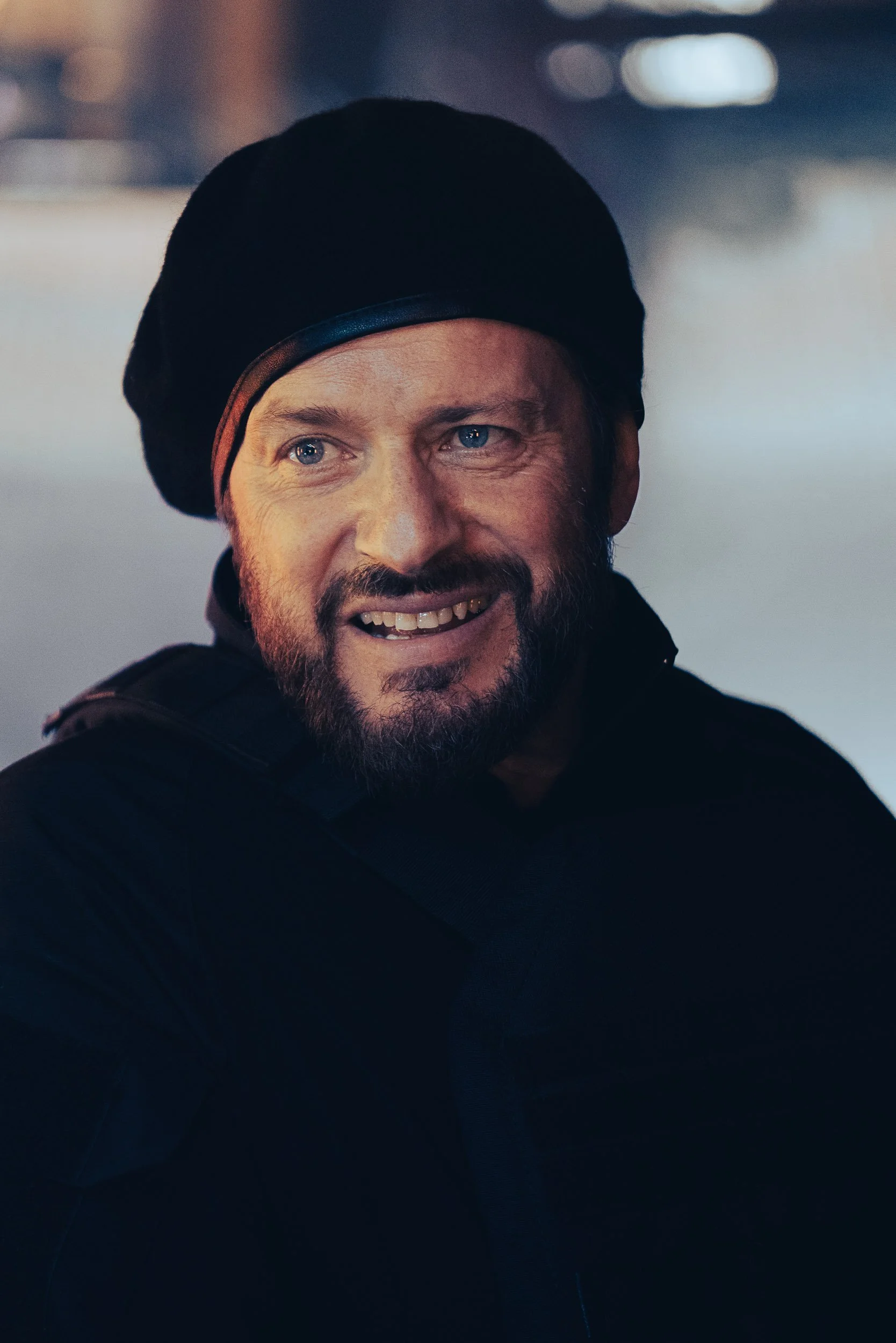 Smiling man wearing a black beret and black jacket