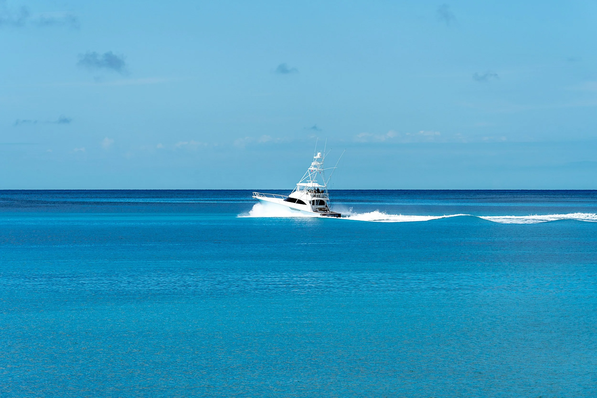 A motorboat speeding on a clear blue ocean under a sunny sky.