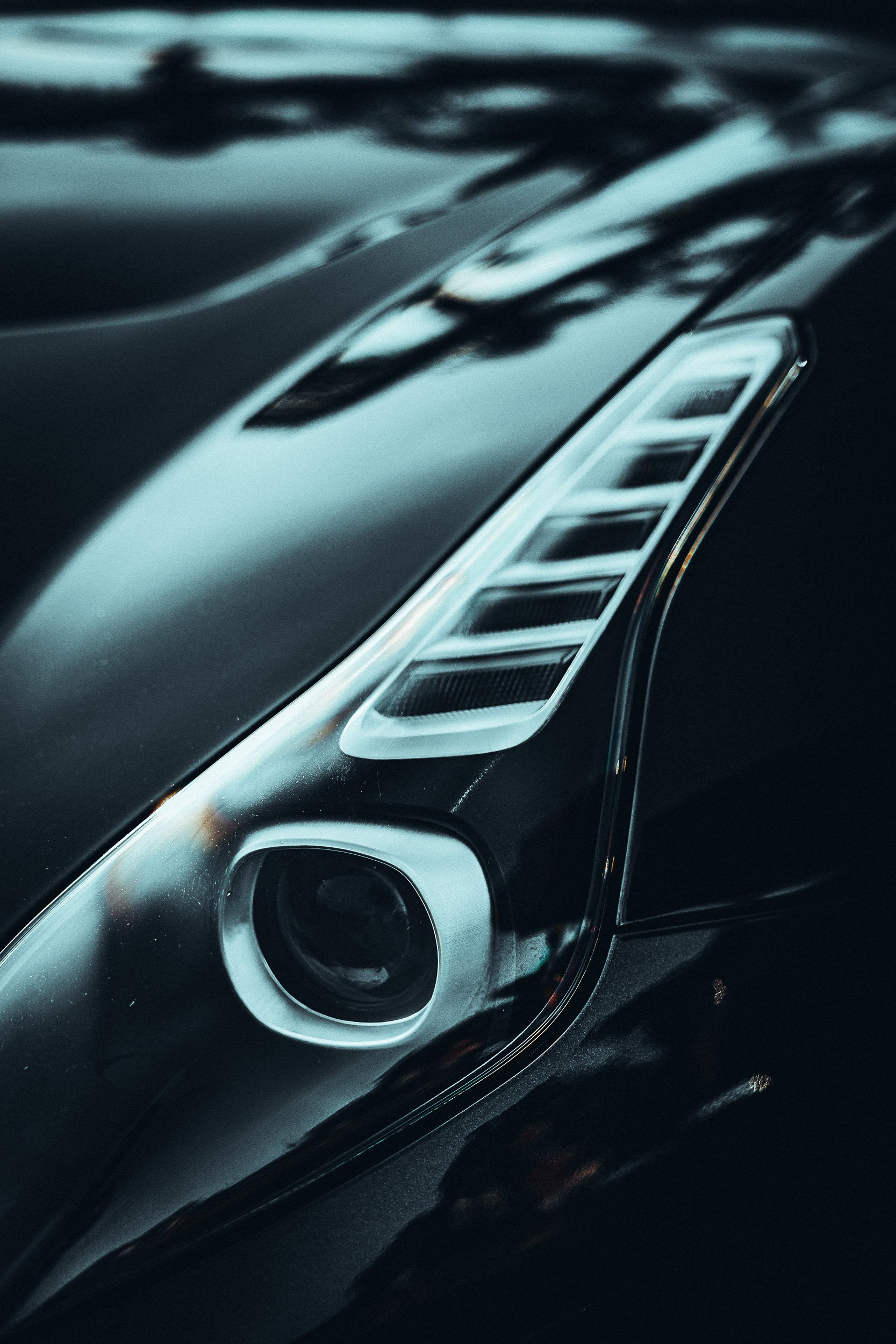 Close-up of car headlight with sleek design and reflective surface.