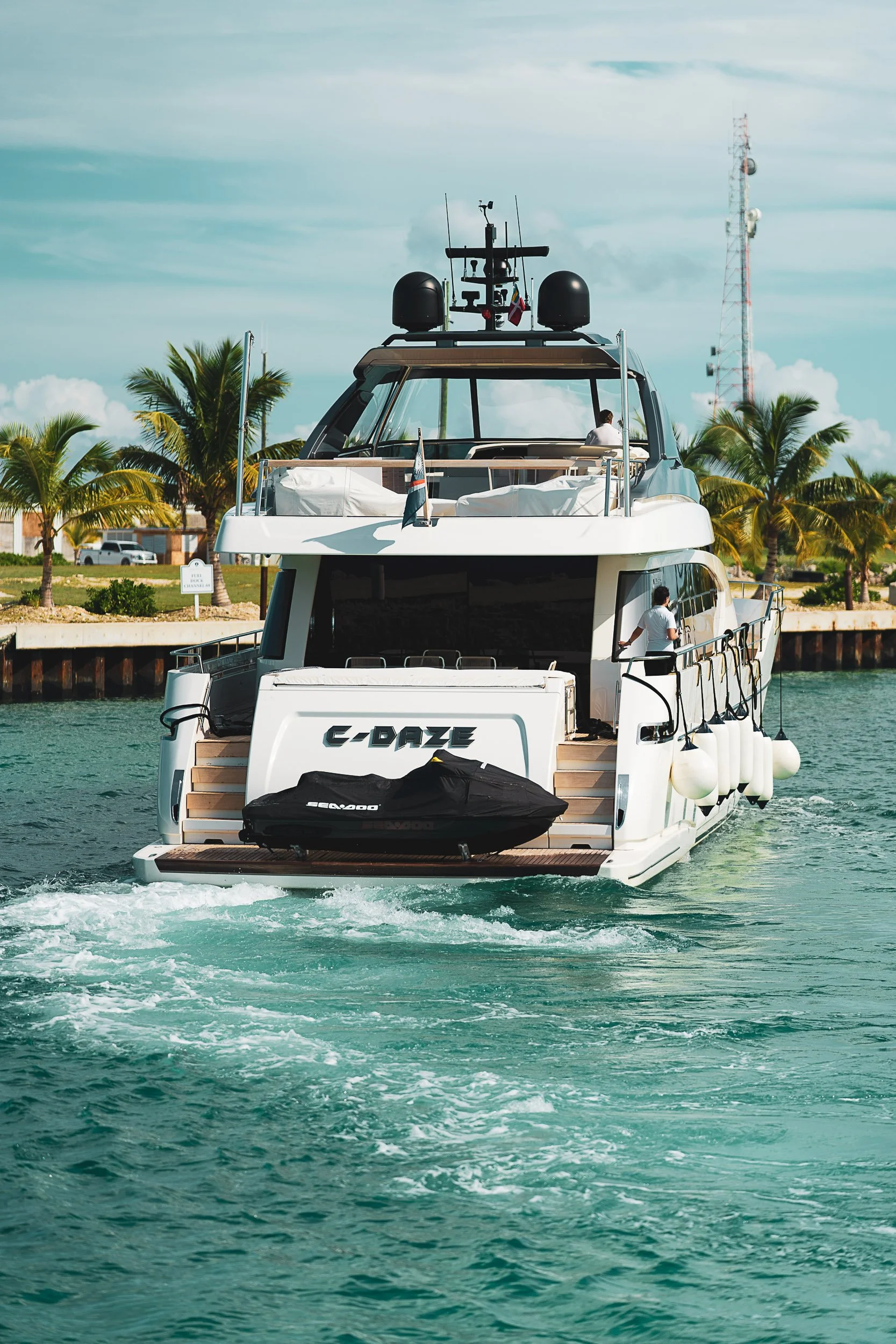 Luxury yacht cruising on clear blue water with palm trees in the background.
