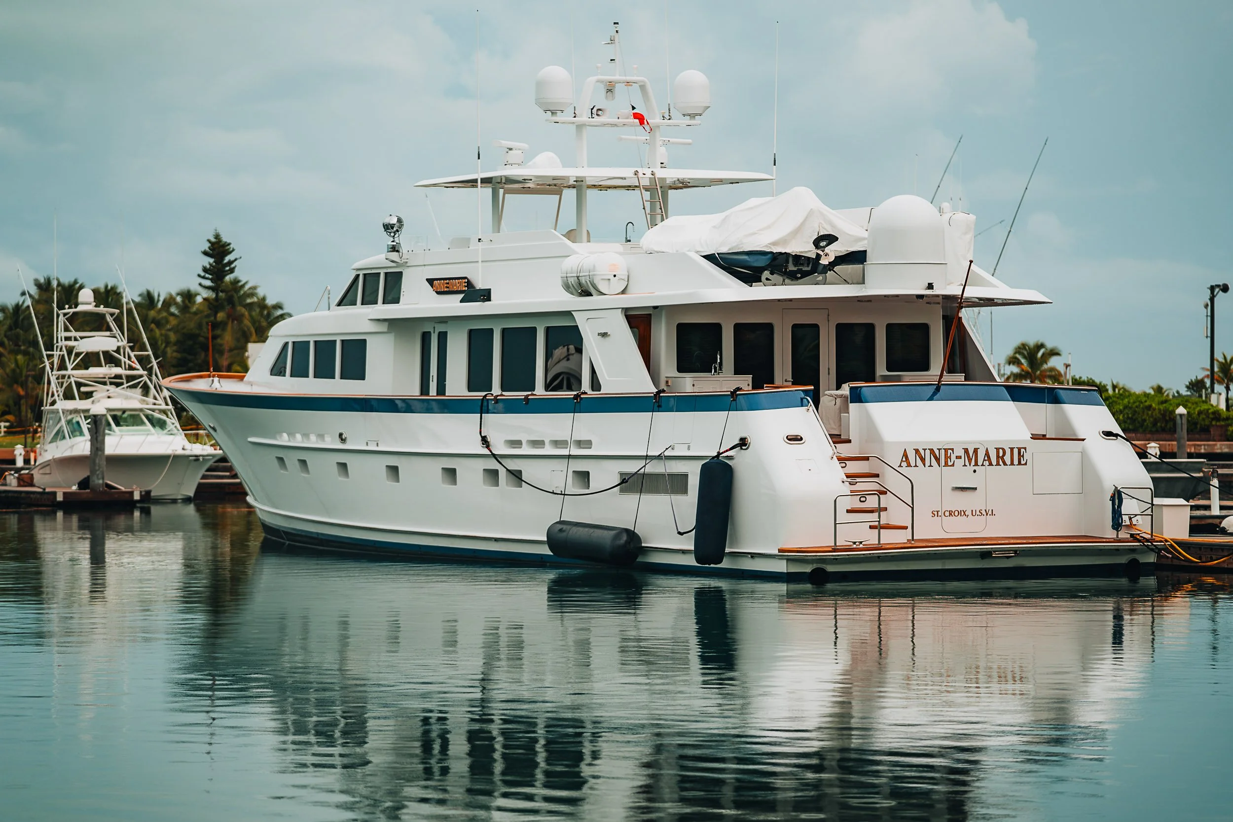 Large luxury yacht named Anne-Marie docked at a marina with a smaller boat in the background.