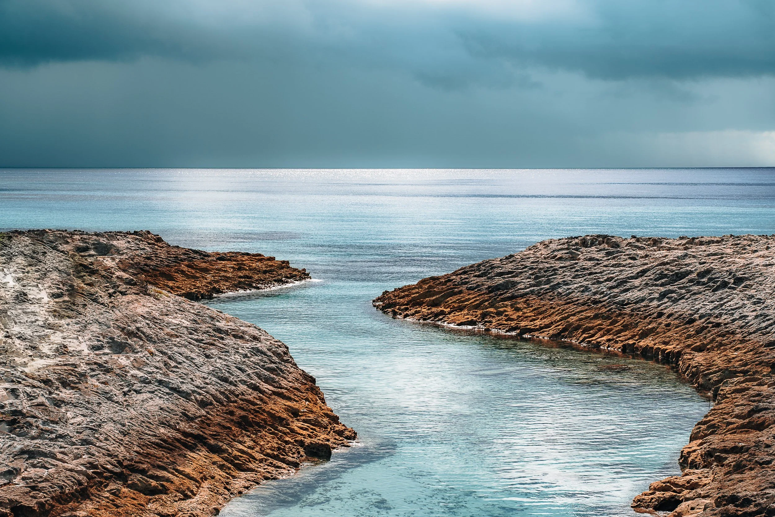 Rocky coastline with clear blue water and overcast sky