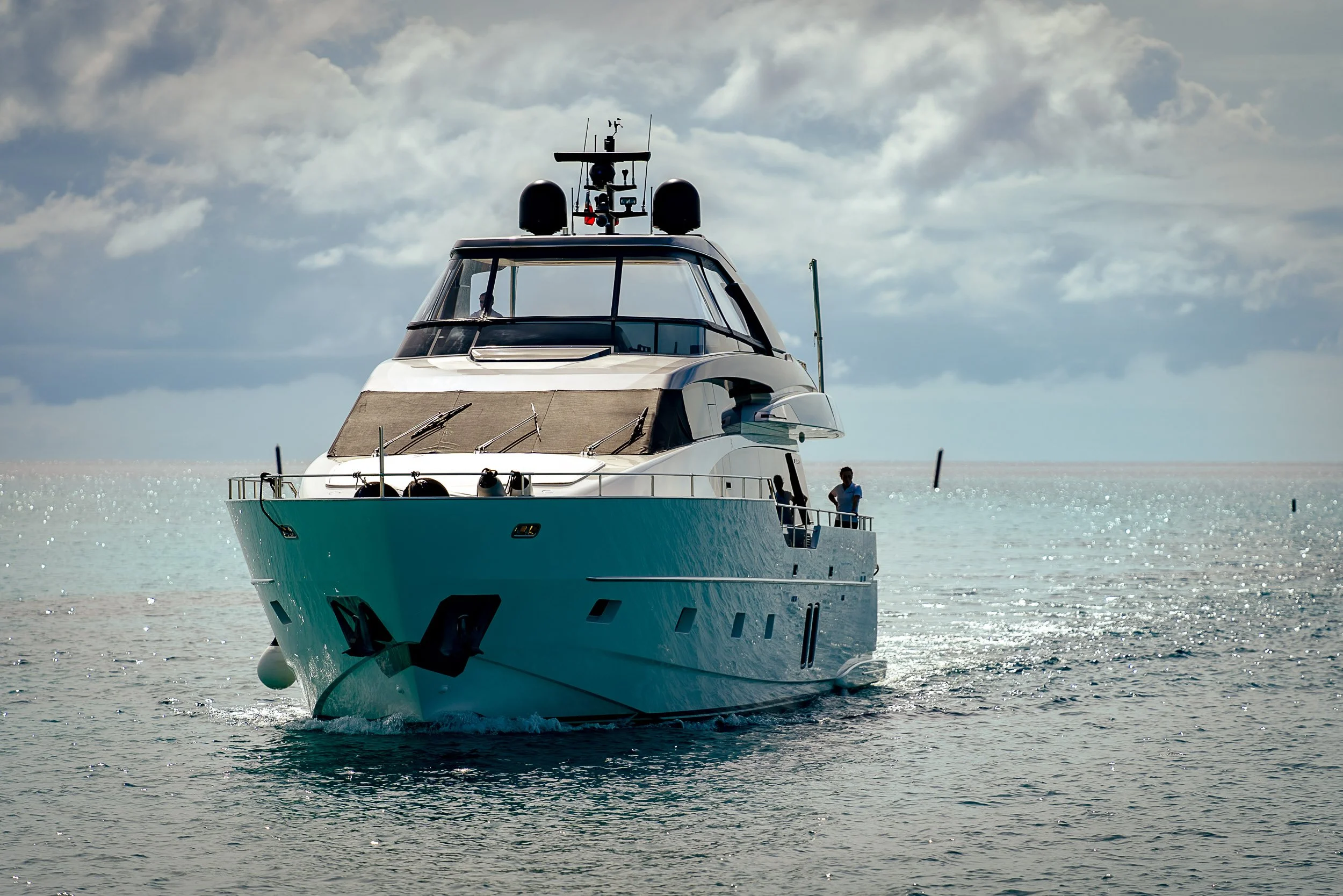 Luxury yacht sailing on a calm ocean with clouds in the sky.