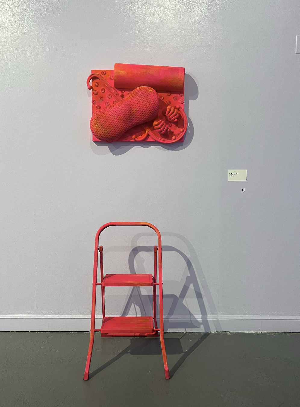 "In Tandem"; Painted Found Object Sculpture; Design Museum of Chicago; Summer 2024; Image Description: A step stool sits on the floor of a white gallery space. On top of the stool is a wall sculpture made from arranged pain management objects such as
