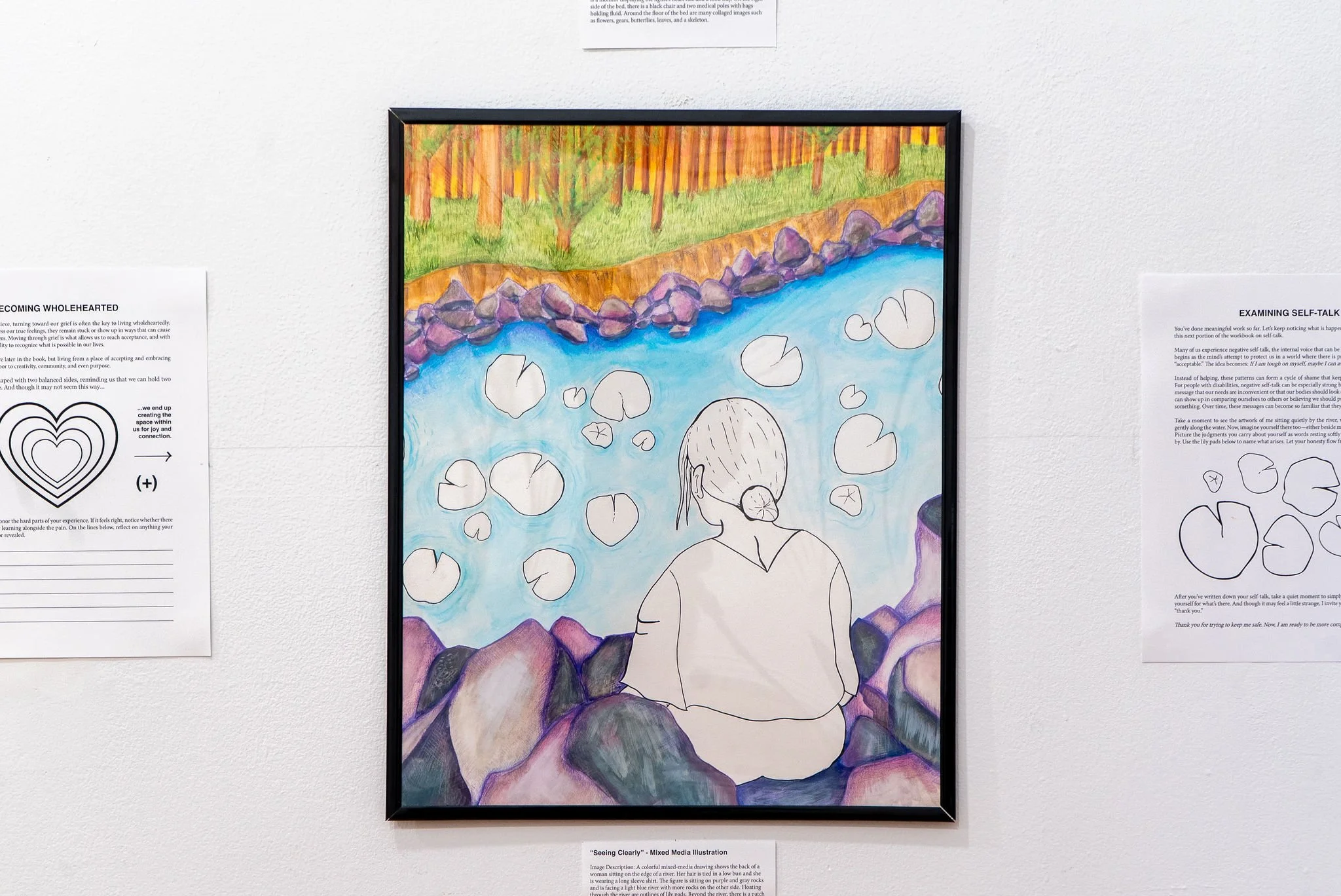 "Seeing Clearly"' Mixed Media Drawing; 9 x 12"; Fall 2025; Image Description: A colorful mixed-media drawing shows the back of a woman sitting on the edge of a river. Her hair is tied in a low bun and she is wearing a long sleeve shirt. The figure is