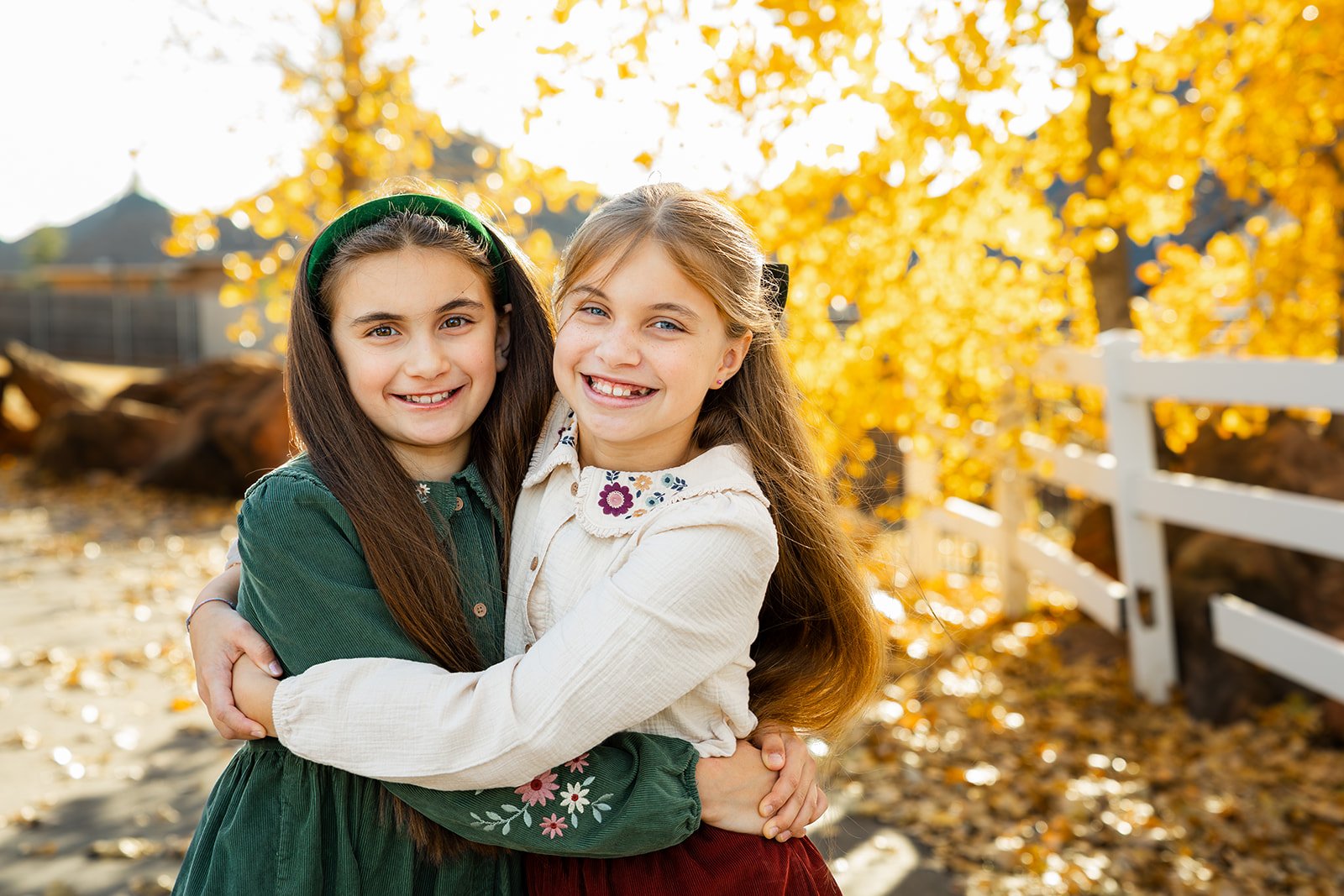 Siblings holding hands while walking through autumn leaves in soft natural light