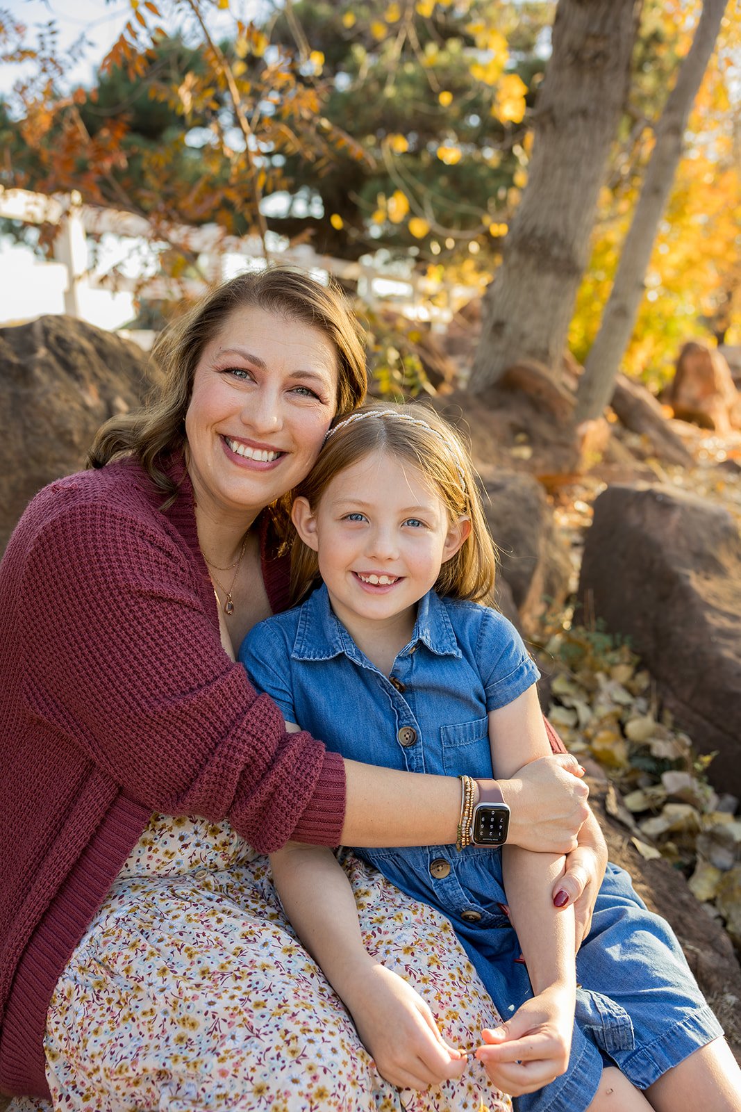 Mom hugging her young daughter close in soft natural light during a story-driven family portrait session