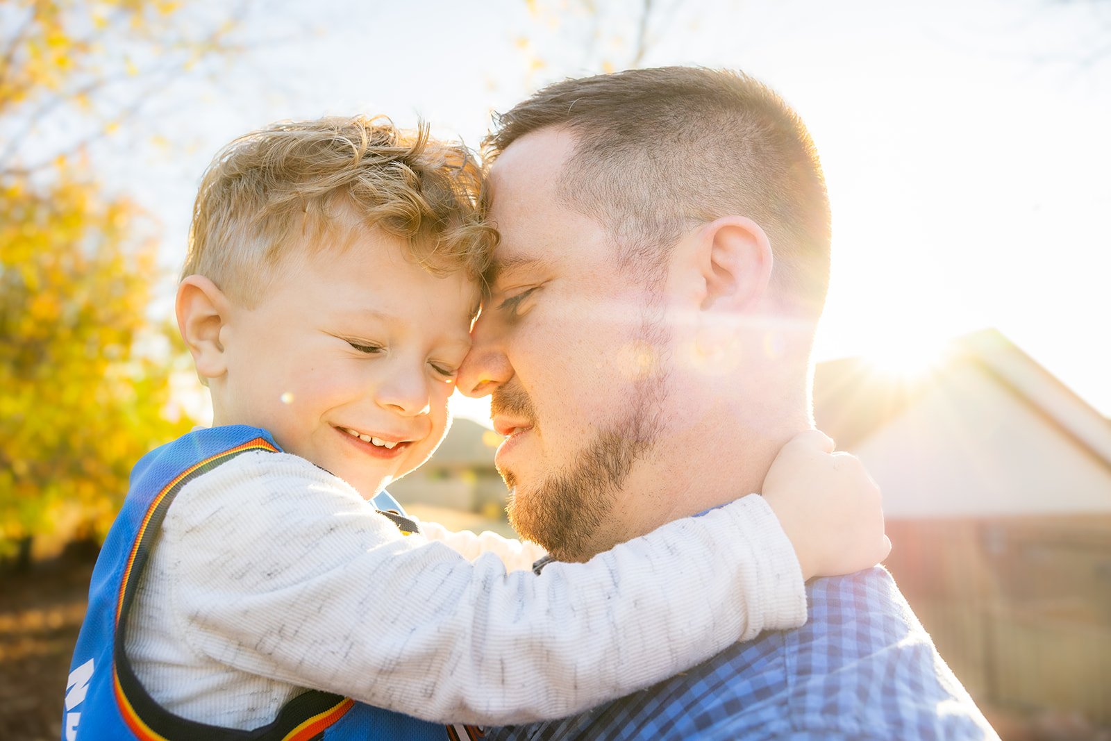 Backlit family portrait with a warm golden hour sun flare glowing behind them in Edmond, Oklahoma