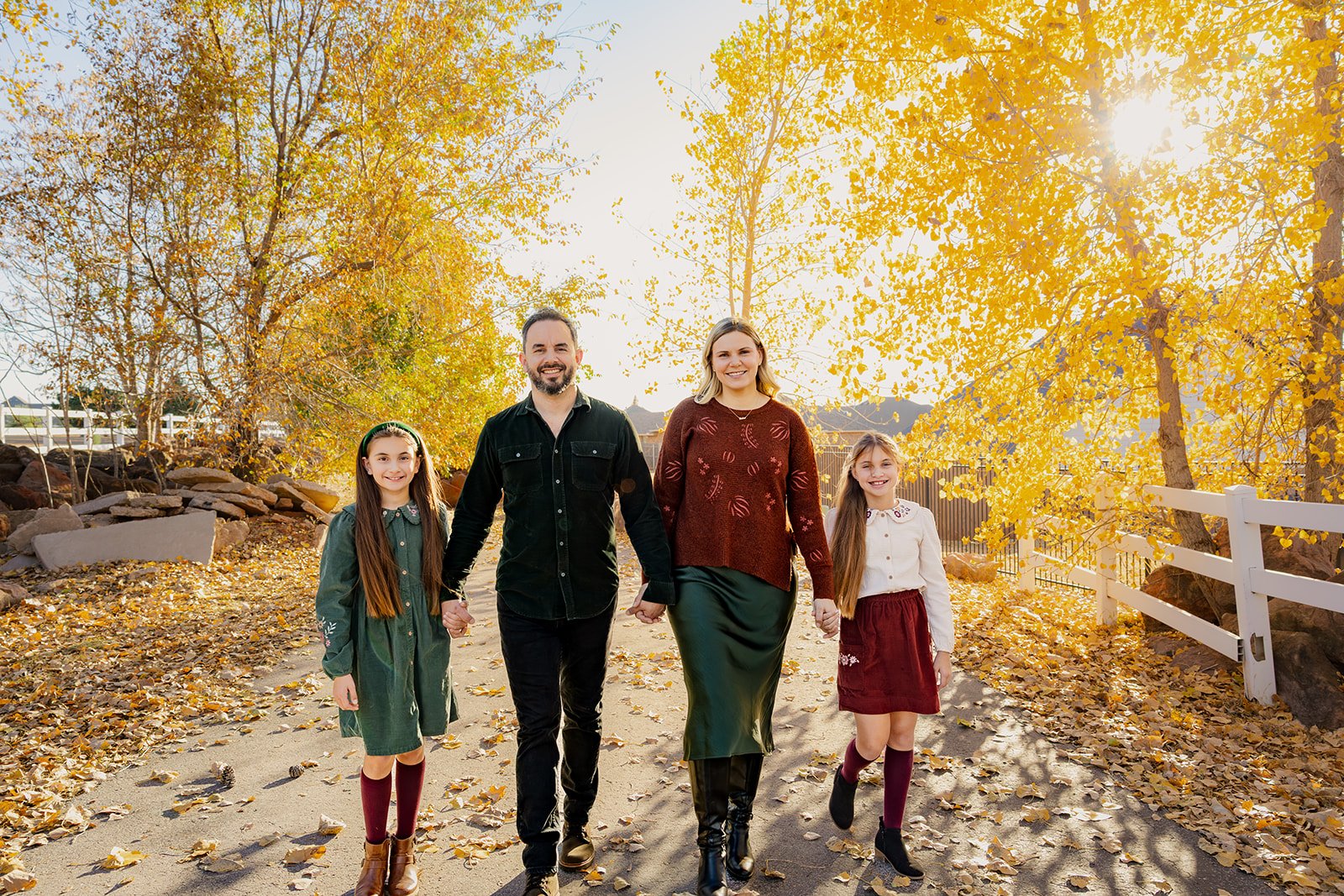 Wide shot of a family standing among colorful fall trees at an outdoor photo location in Edmond, Oklahoma