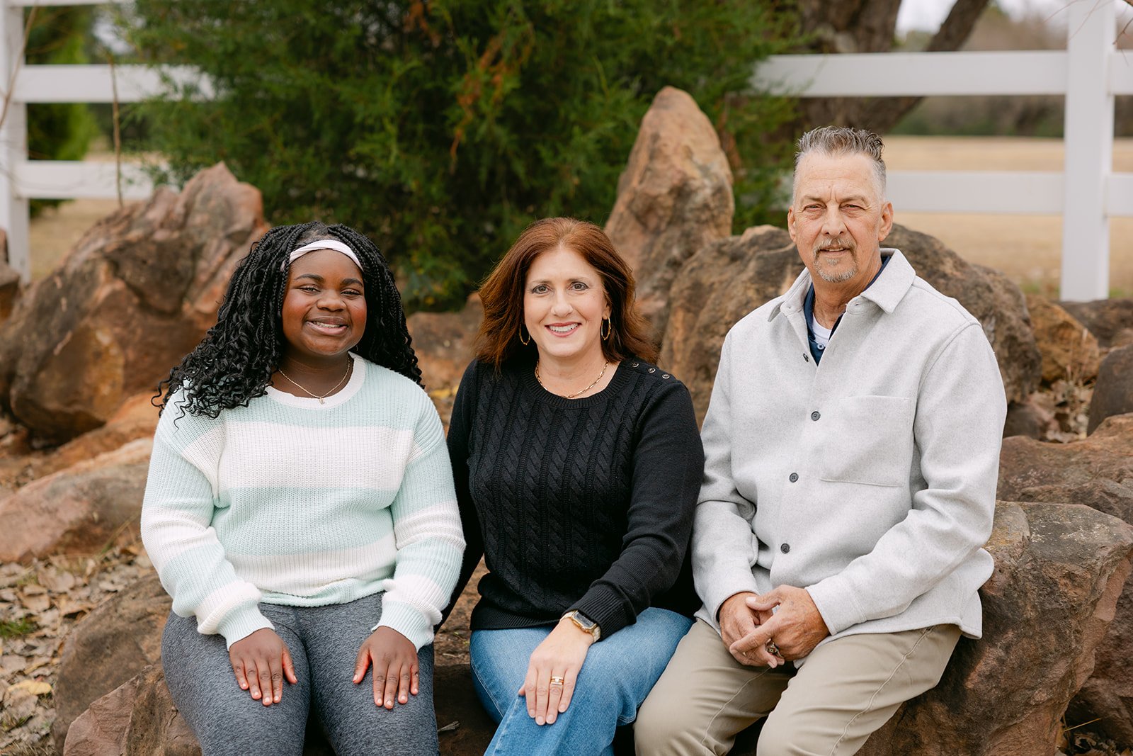 Mom, dad, and daughter snuggled together in warm golden hour light during a fall family portrait session near Oklahoma City