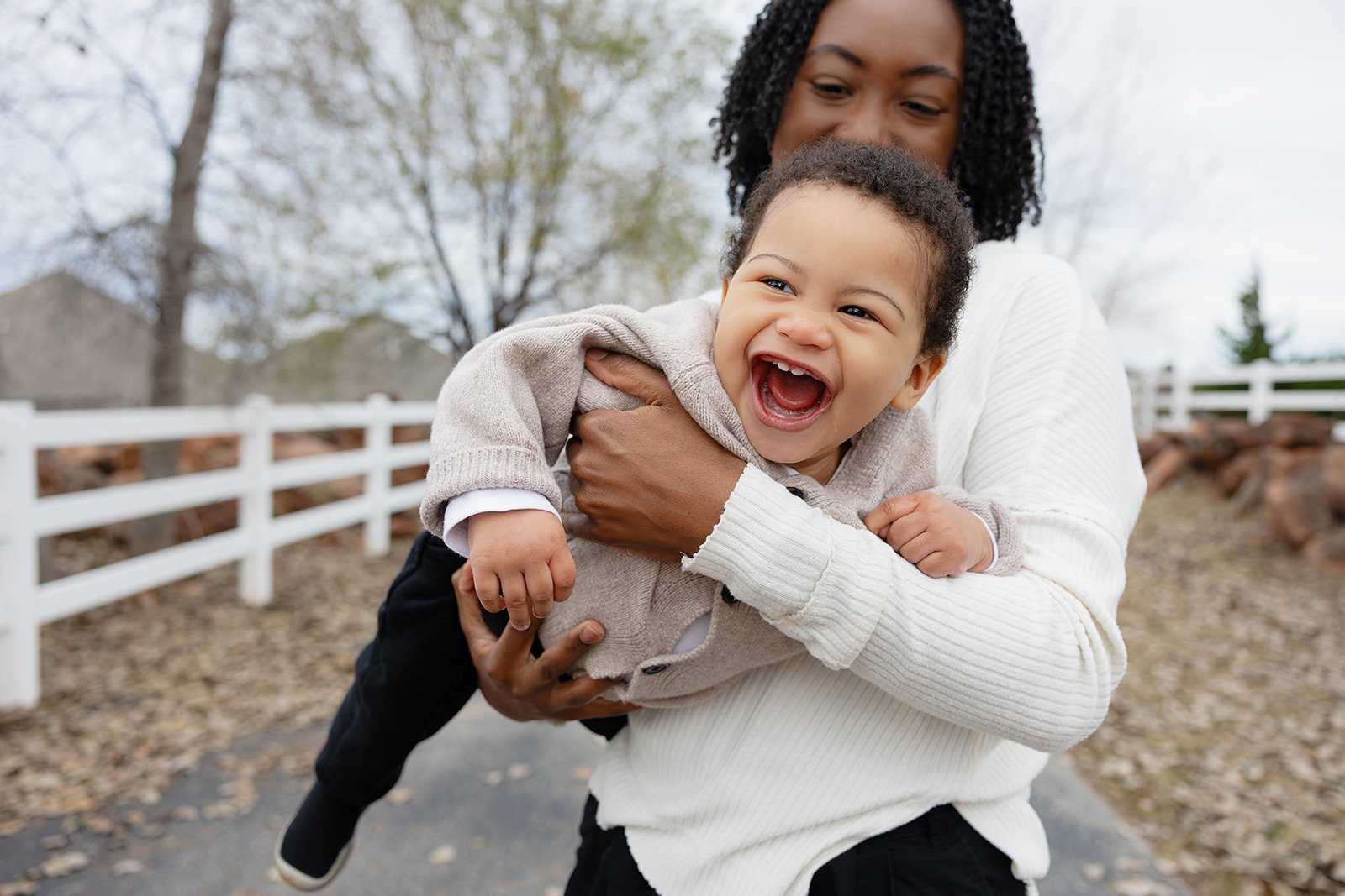Little boy laughing and playing airplane with mom autumn leaves during a lifestyle photography fall mini session
