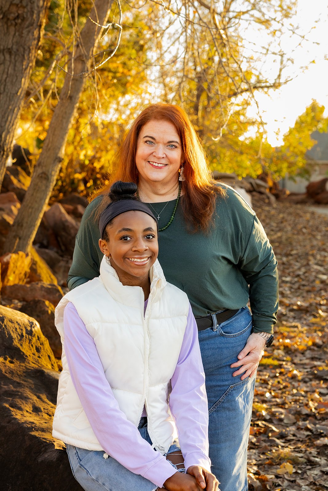 Mother and daughter smiling cheek to cheek among fall leaves during a mini session in Edmond, OK