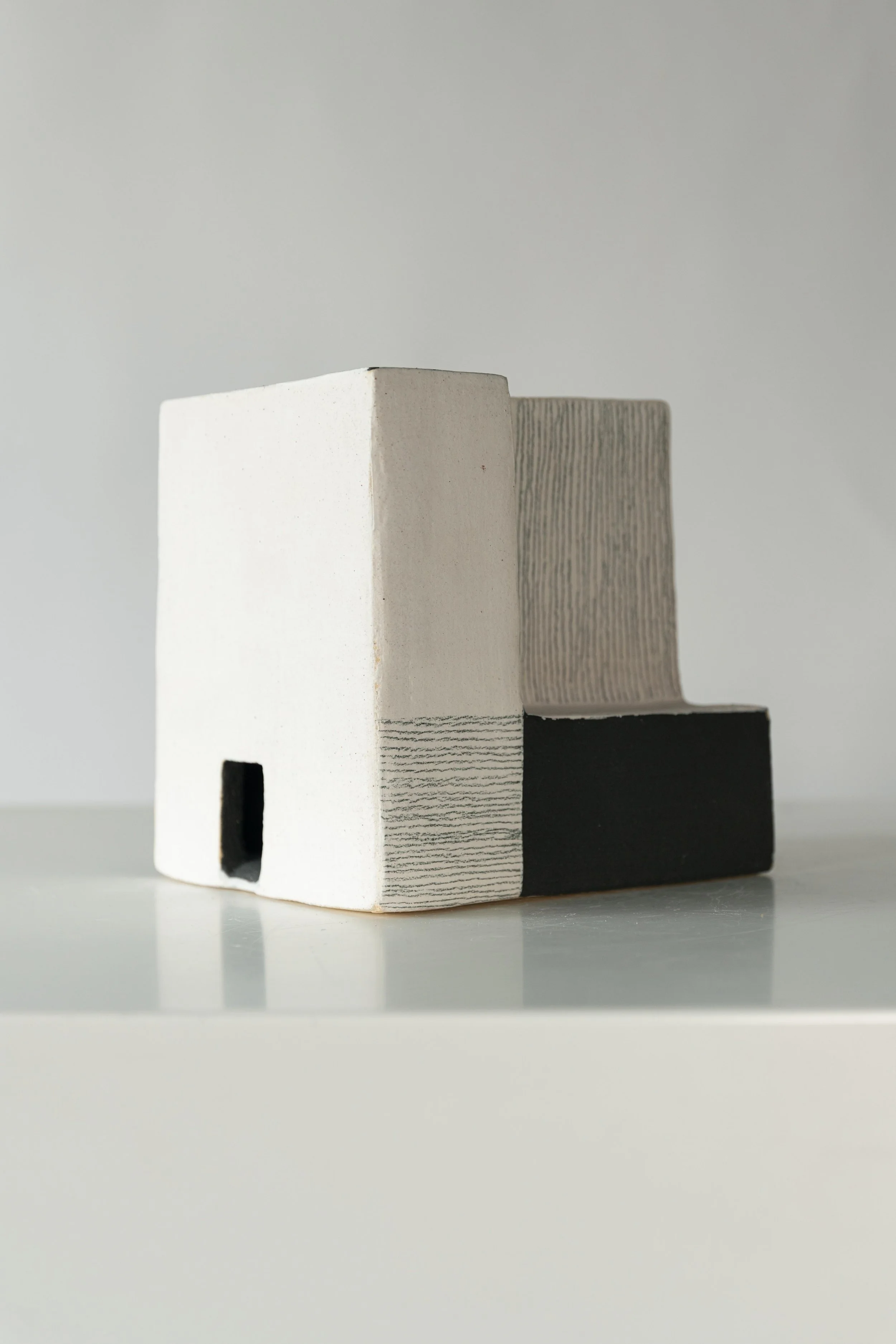 Close-up of three ceramic vases with different textures and colors, placed on a white surface.