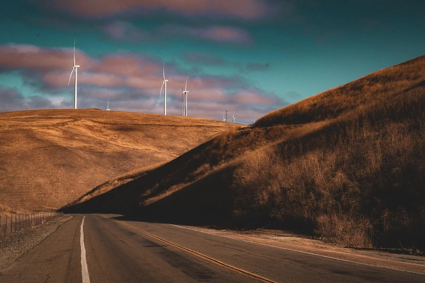 The road cuts through rolling hills where shadows stretch deep, and turbines rise above the horizon like quiet sentinels turning with the wind. A meeting of stillness and motion, solitude and energy.

#AltamontPass #WindTurbines #CaliforniaLandscapes