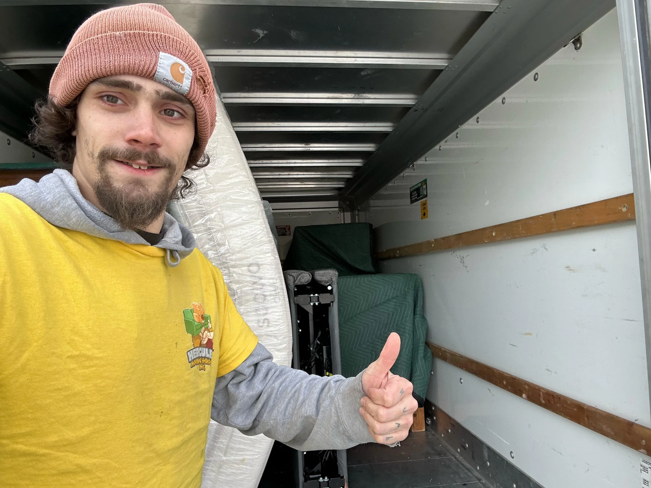 Aerial view of downtown Albany, New York, featuring modern skyscrapers, including some government buildings. The cityscape stretches to a horizon of trees and hills under a cloudy sky.