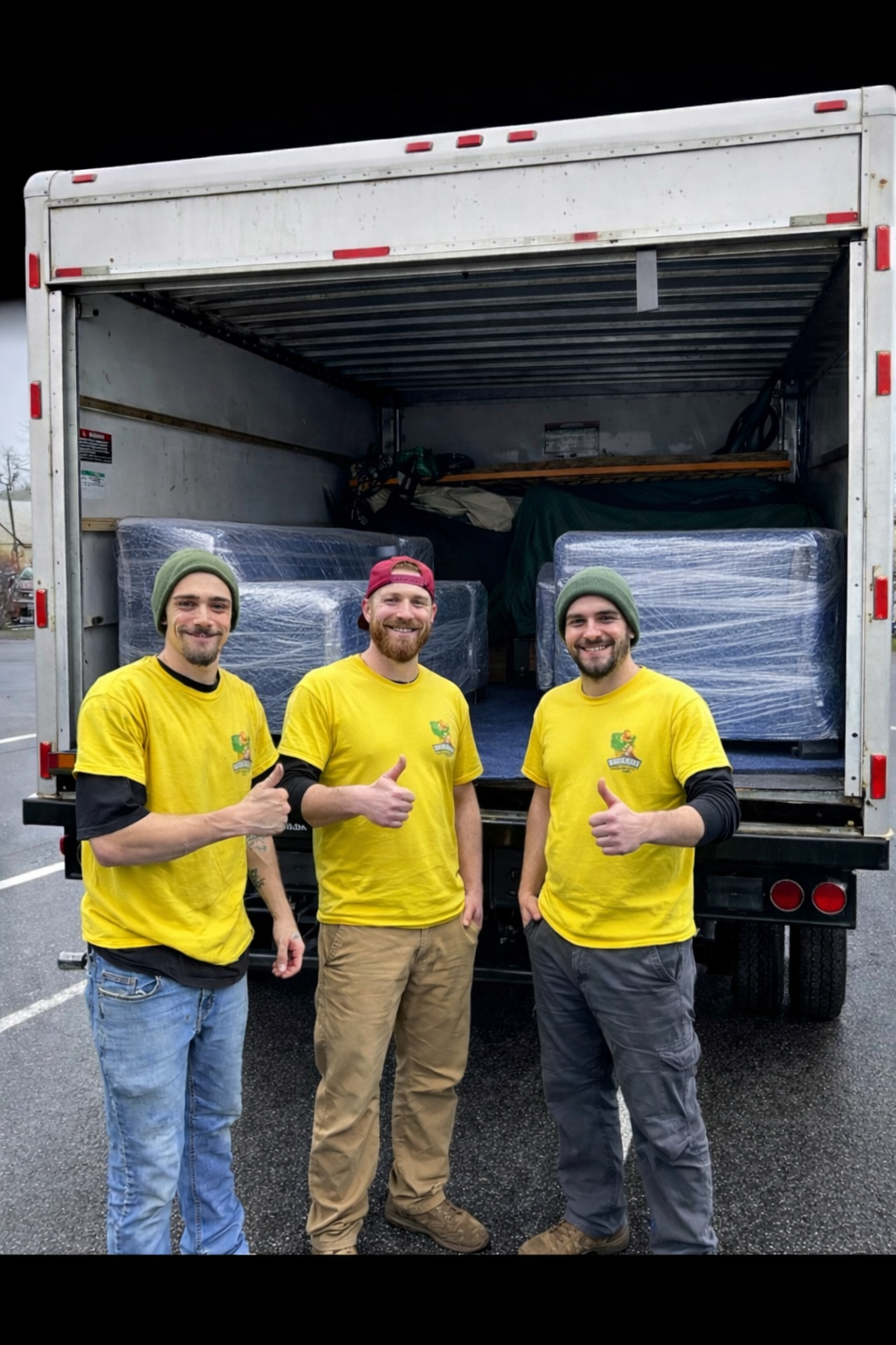 three movers moving company thumbs up with a wrapped furniture and truck in background