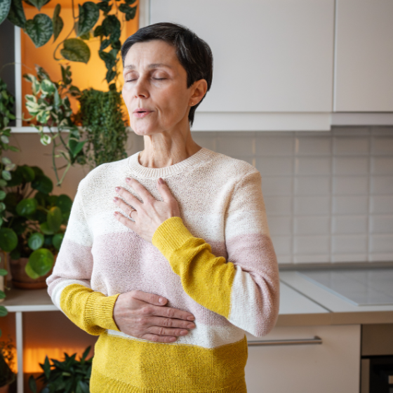 woman breathing with one hand on her belly and one hand on her heart
