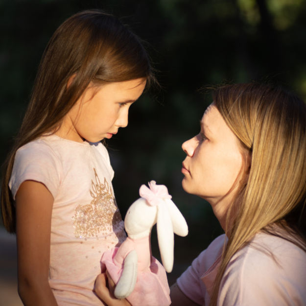 mother holding toy for sad child