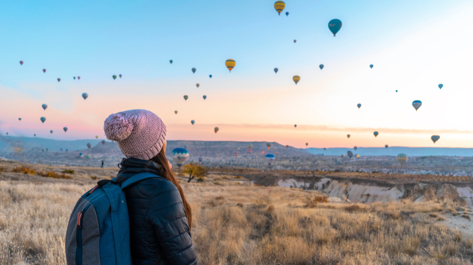 Woman mindfully watching hot air balloons floating in the sky, symbolising thoughts passing by