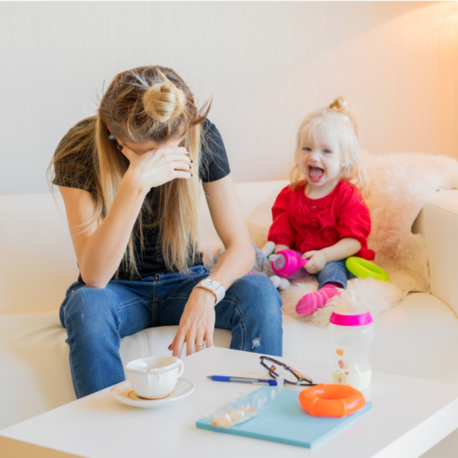 mother burnt out sitting on couch with toddler