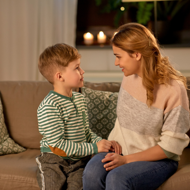 Mum sitting with her young son and talking with him at home.