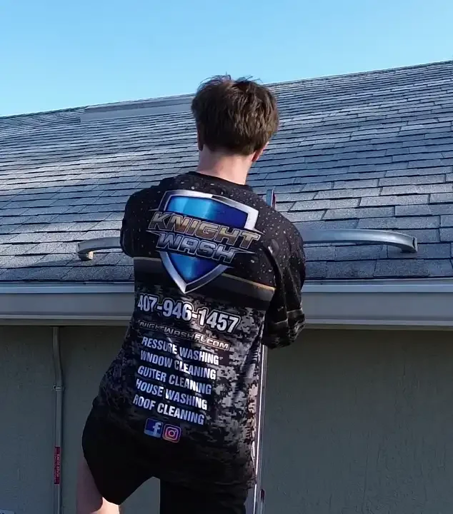 Knight wash technician on a ladder cleaning an orlando home's gutters