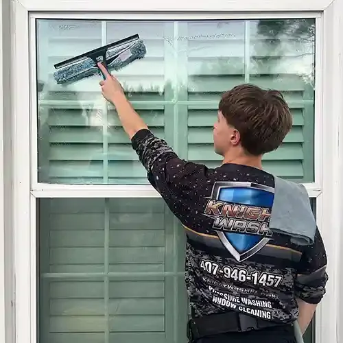A Knight Wash technician window cleaning with a mop and squeegee on a Orlando home