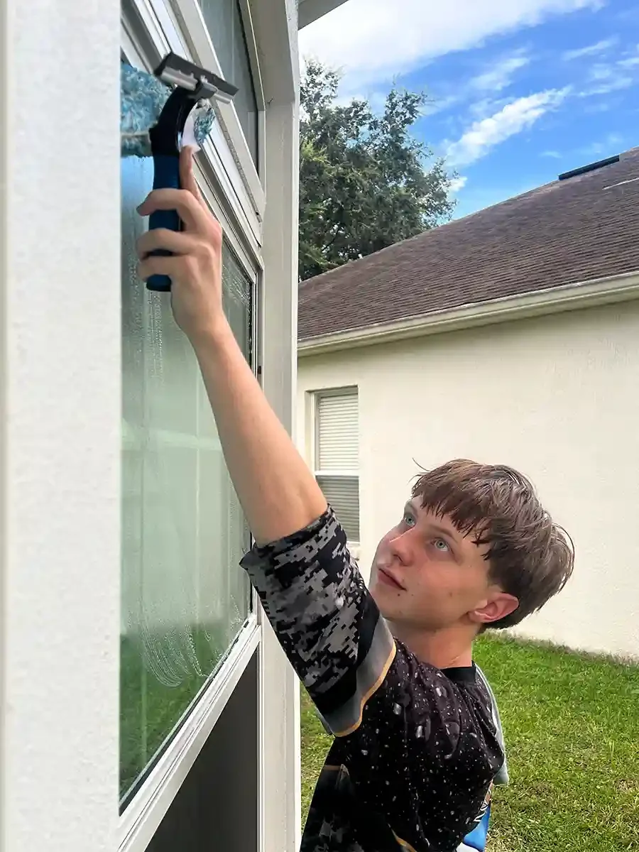 Knight wash technician using a squeegee to clean the windows on an Orlando home