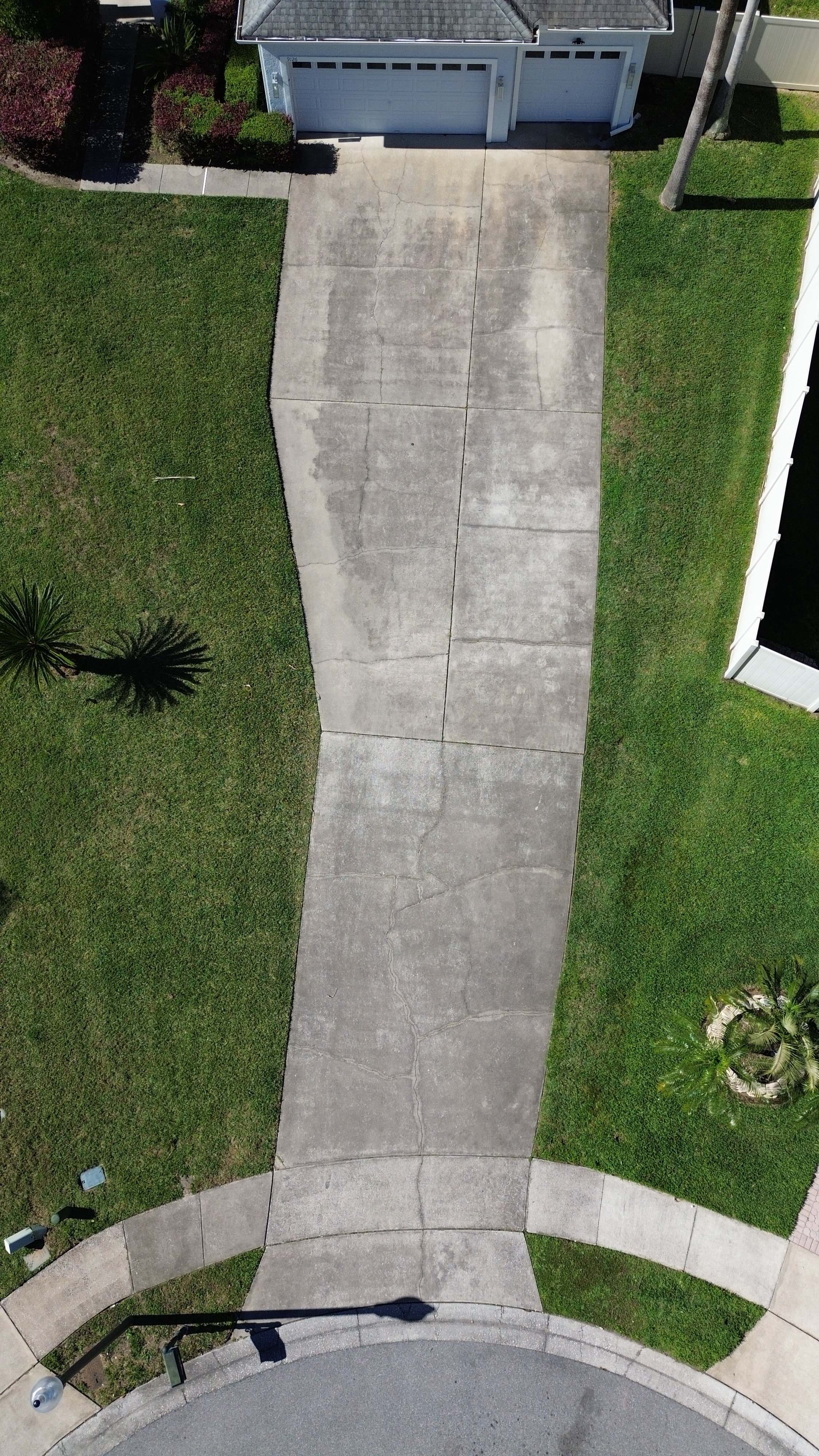 Dirty driveway covered in black streaks before pressure washing