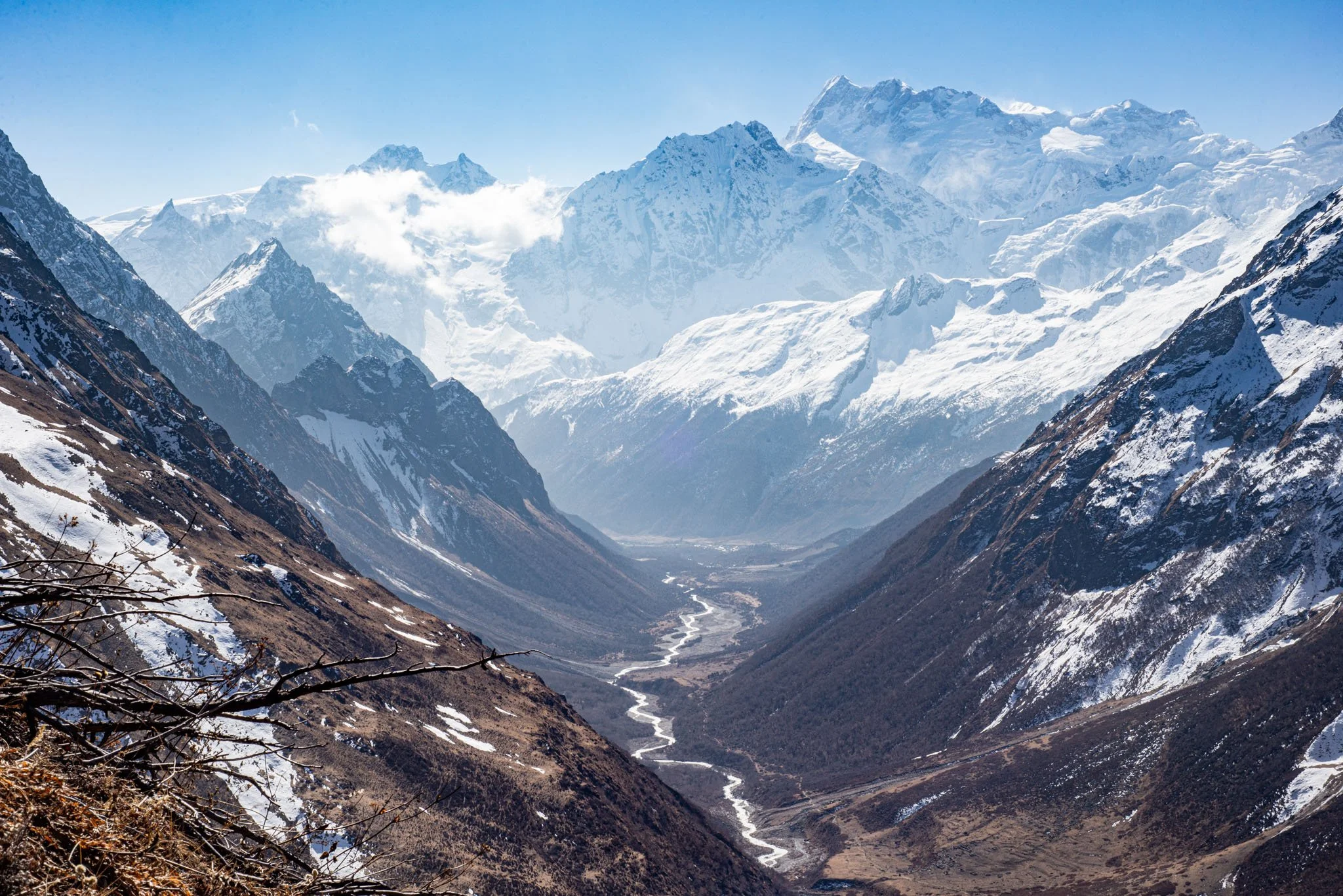 Snow-capped mountain range with a deep valley and a winding river.
