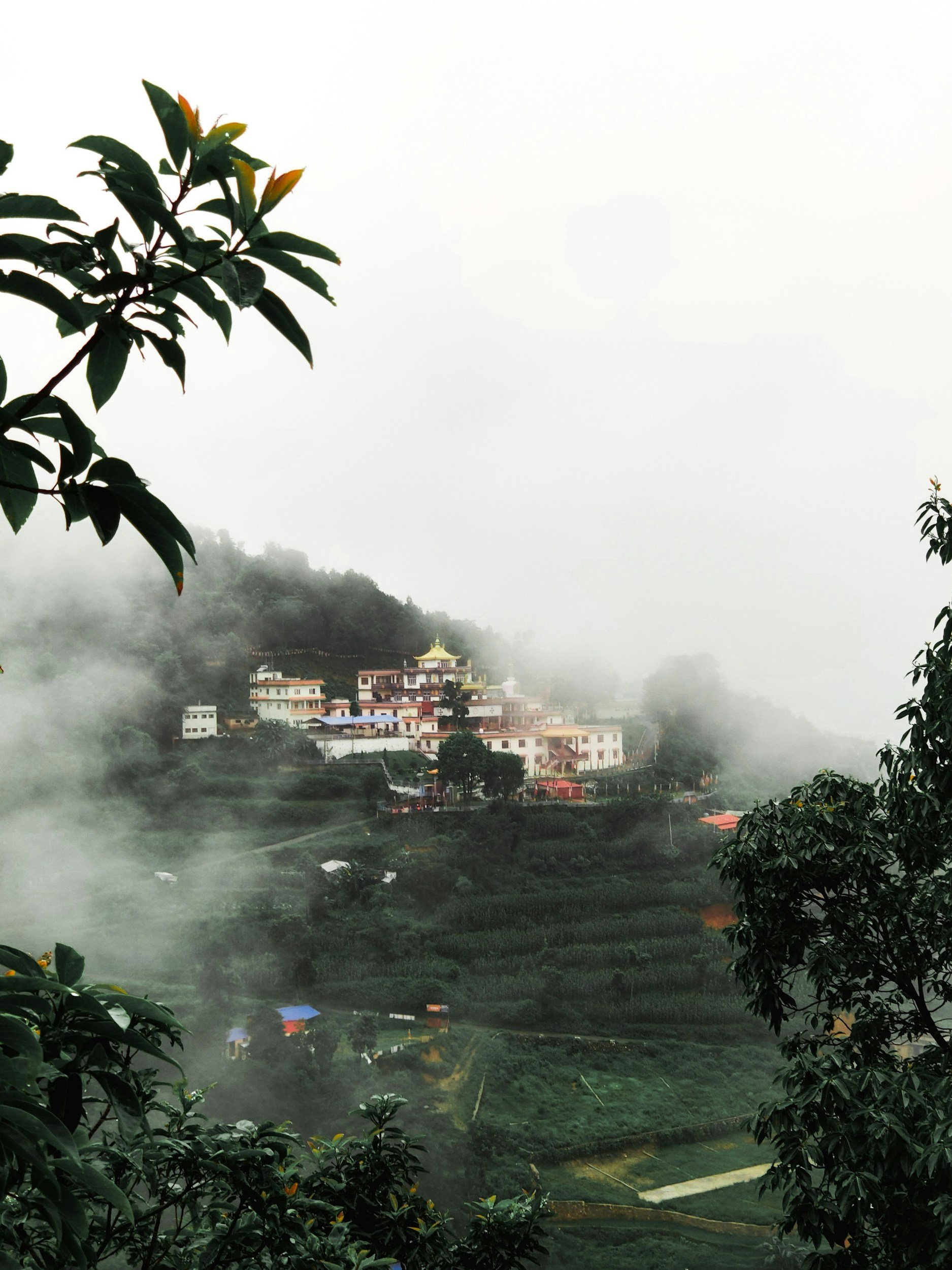 A Buddhist monastery across the valley on a cloudy day in the mountains of Nepal.