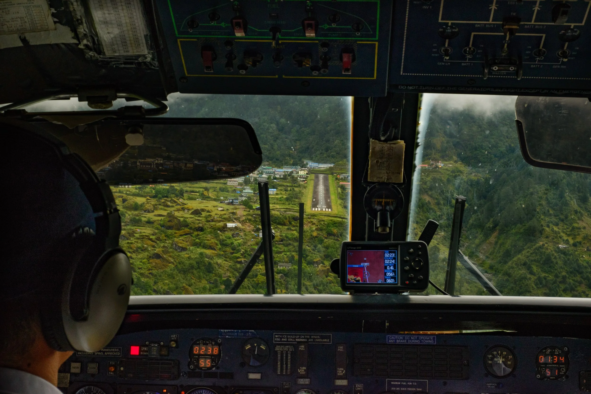 Plane cockpit approaching runway surrounded by mountains