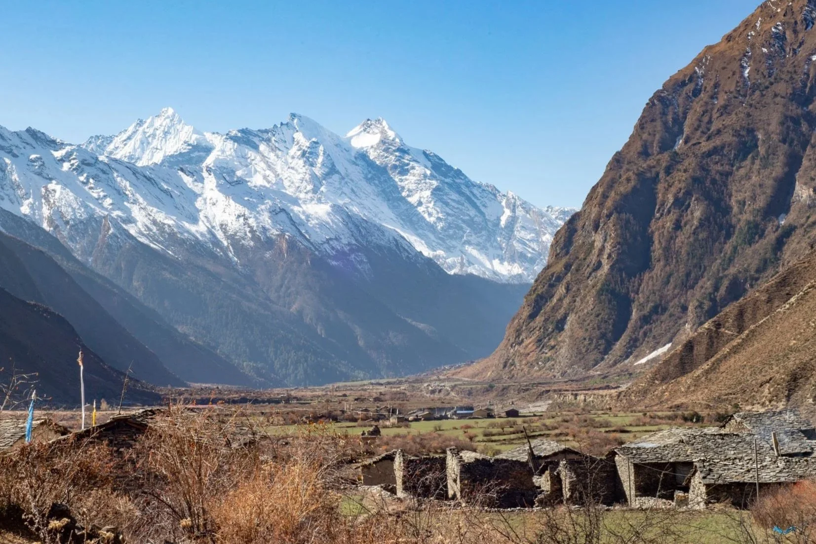 Traditional stone huts in the foreground with Himalayan mountains rising in the background