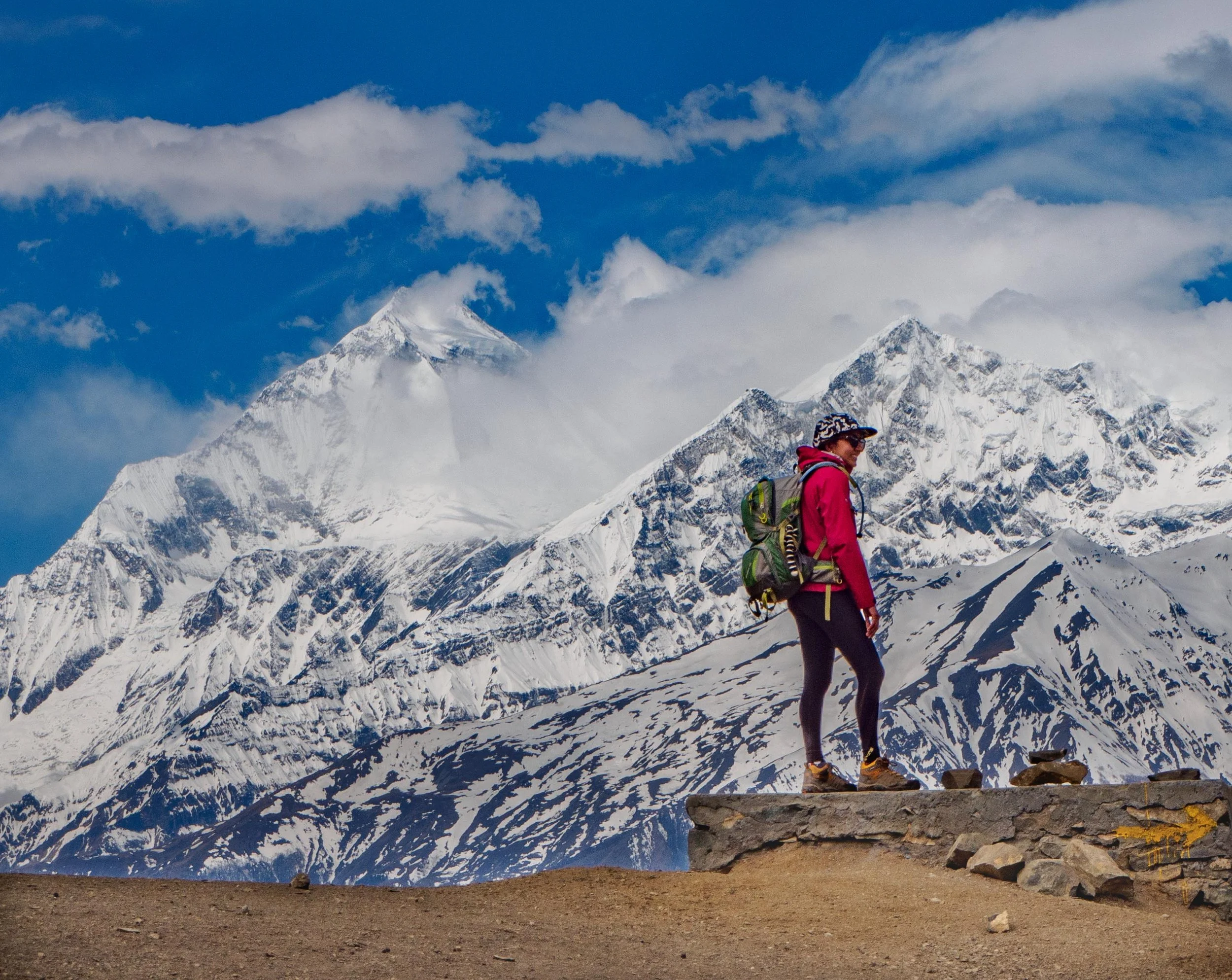 A trekker standing in front of Dhaulagiri with surrounding Himalayan peaks rising in the background.