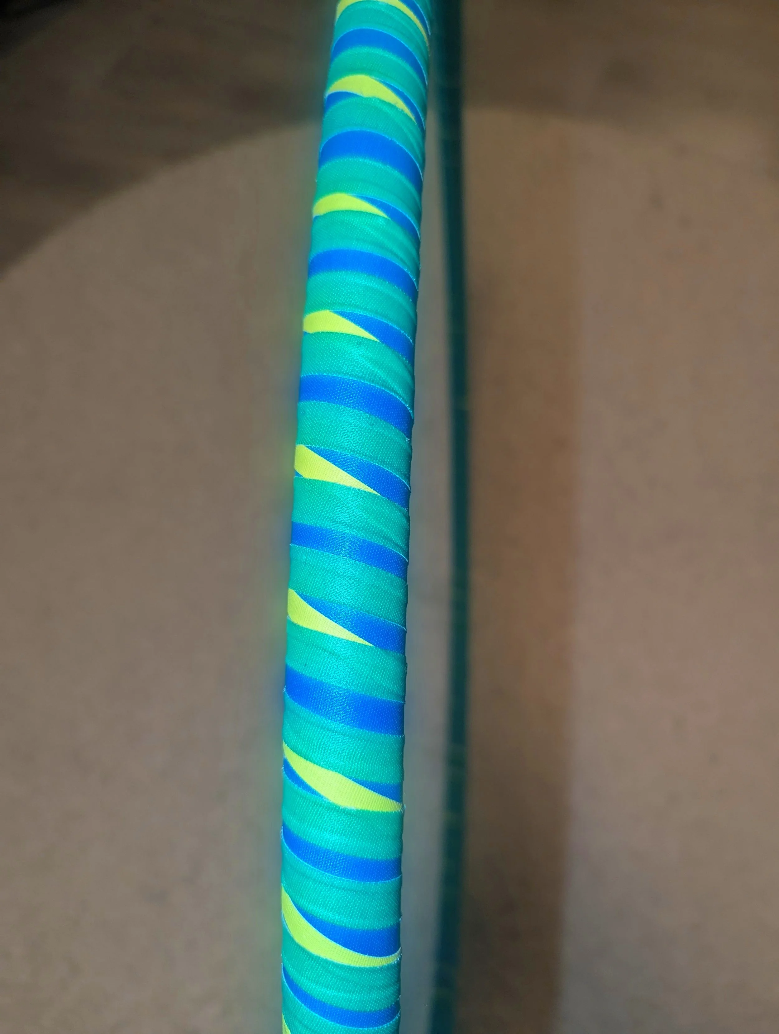 Nahaufnahme eines Hula-Hoop-Reifens mit blau-grünem spiralförmigem Muster auf einem hellen Hintergrund.