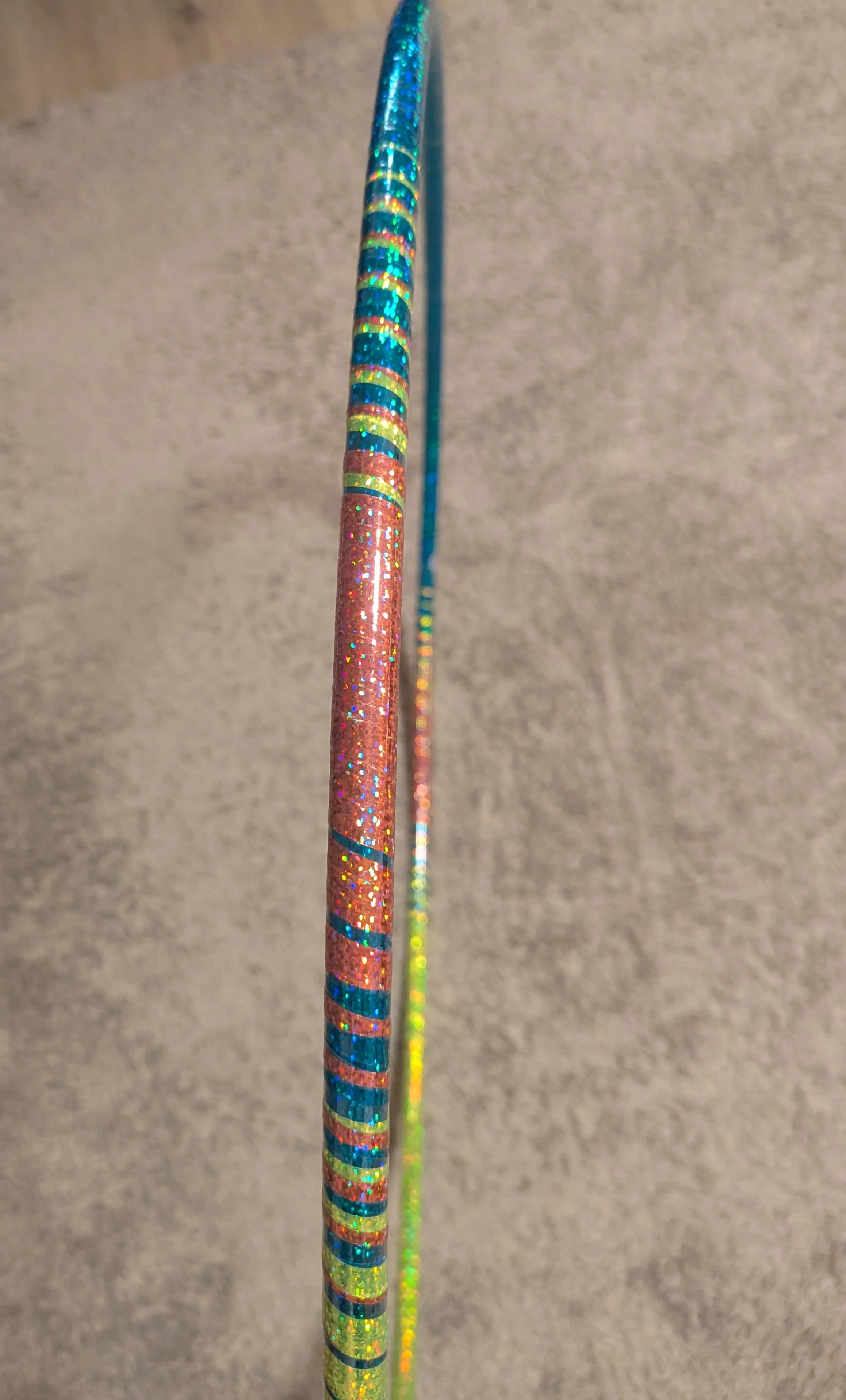 Seite eines schimmernden Hula-Hoop-Reifens auf einem grauen Hintergrund.