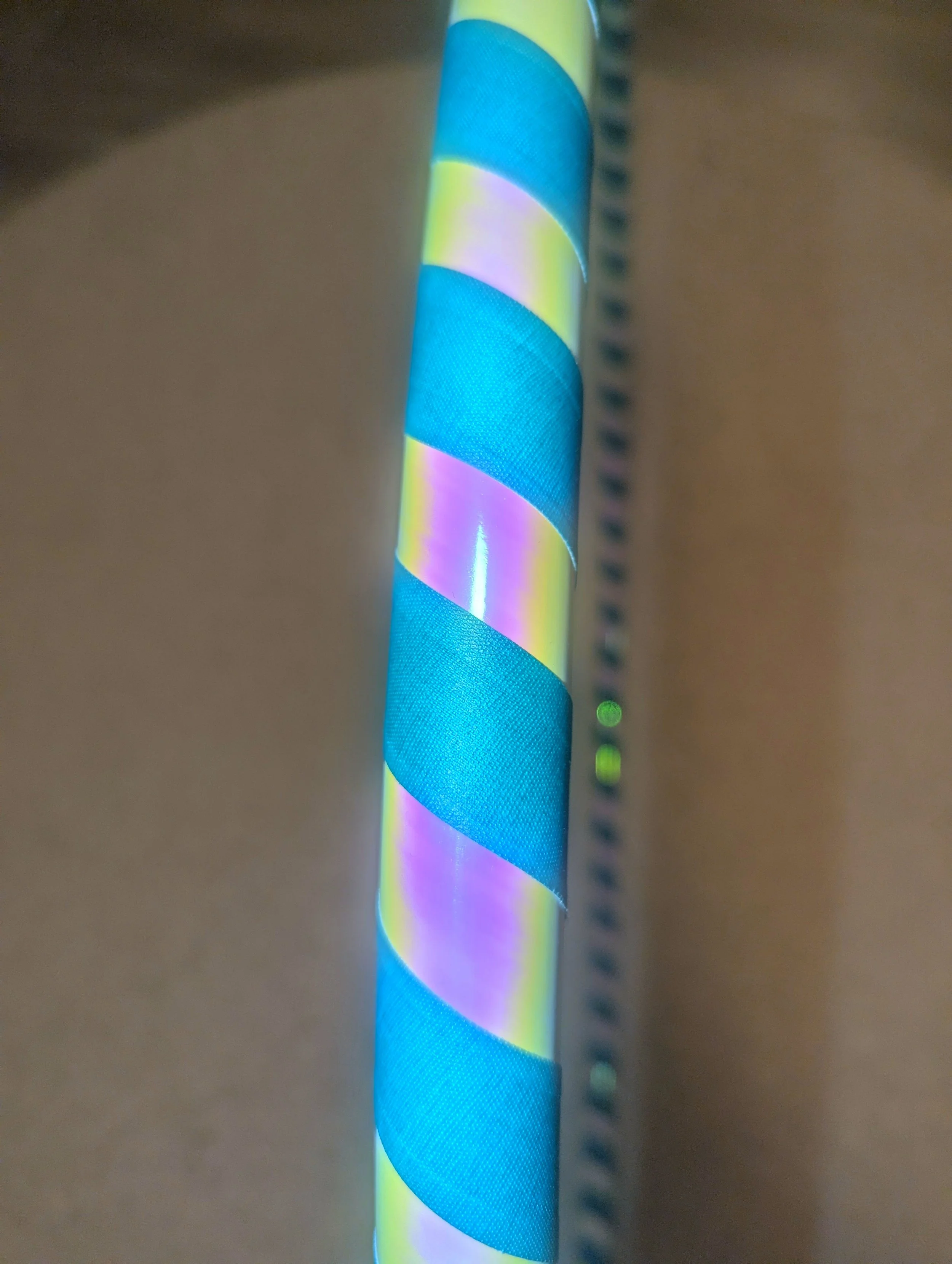 Nahaufnahme eines Hula-Hoop-Reifens mit buntem Streifenmuster in Blau, Gelb und Rosa.